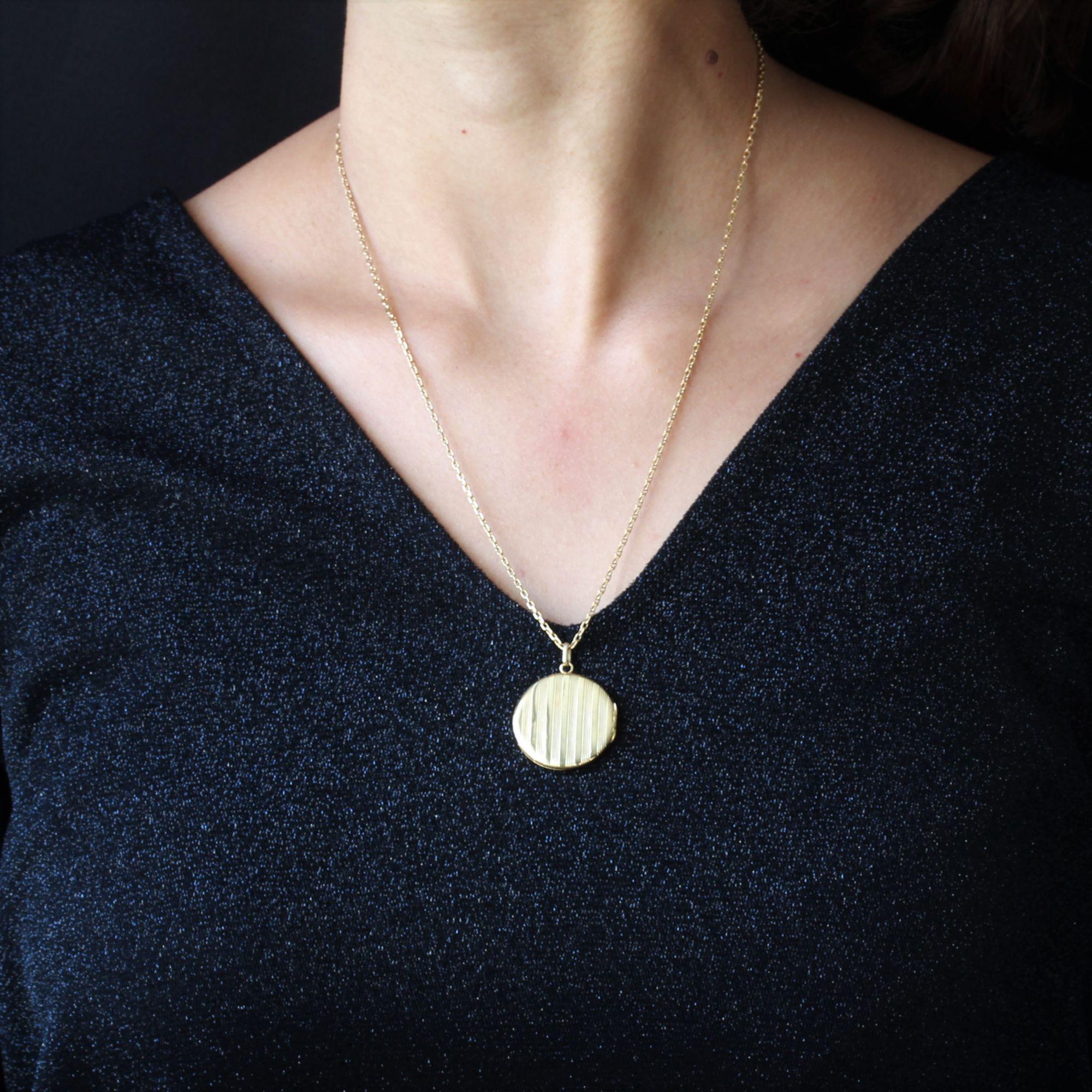 Pendant and chain in 18 karat yellow gold, eagle head hallmark.
Of round shape, opening, this antique medallion is decorated on its two faces of vertical striations alternated with polished pattern. It is supported by a yellow gold chain made of