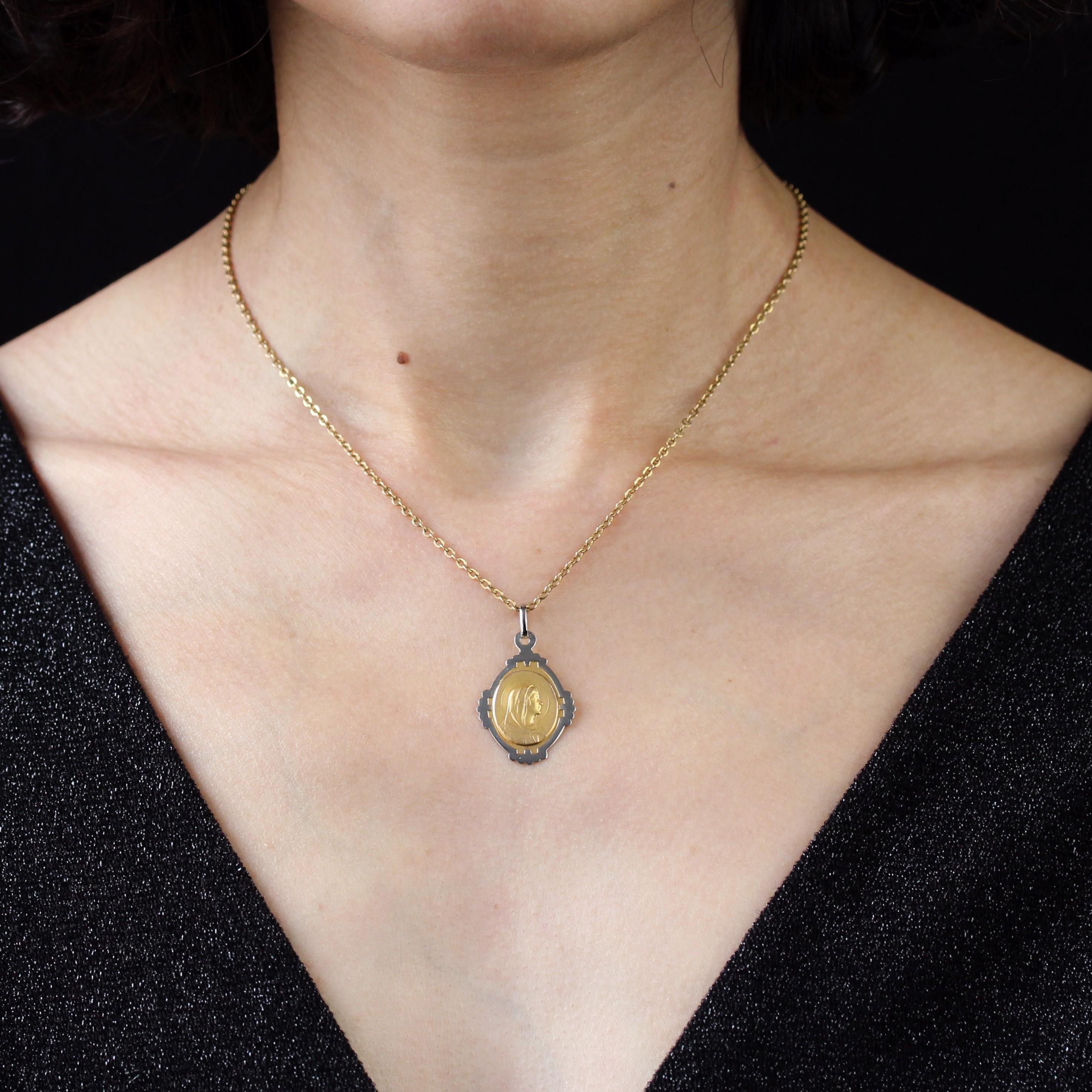 Médaille en or jaune et blanc 18 carats, poinçon tête d'aigle.
Médaille antique de forme ovale, elle est multilobée aux quatre points cardinaux en or blanc, le centre représentant la Vierge Marie en or jaune mat. Le dos de ce bijou Art déco est