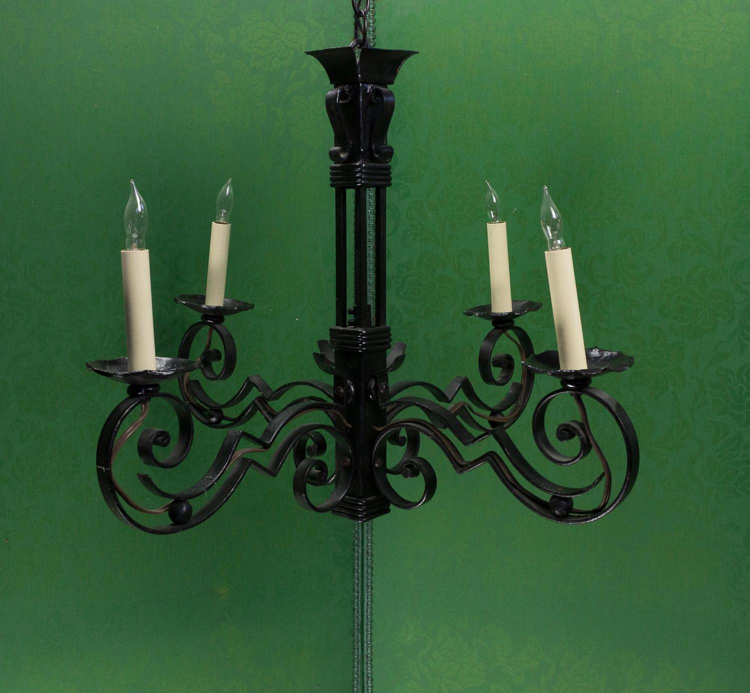 This French 1930s black iron chandelier is a unique piece that is sure to become the centerpiece of any room. Crafted in an Art Deco style, the chandelier boasts delicate intricate scrolled iron detailing, showcasing the craftsmanship and attention