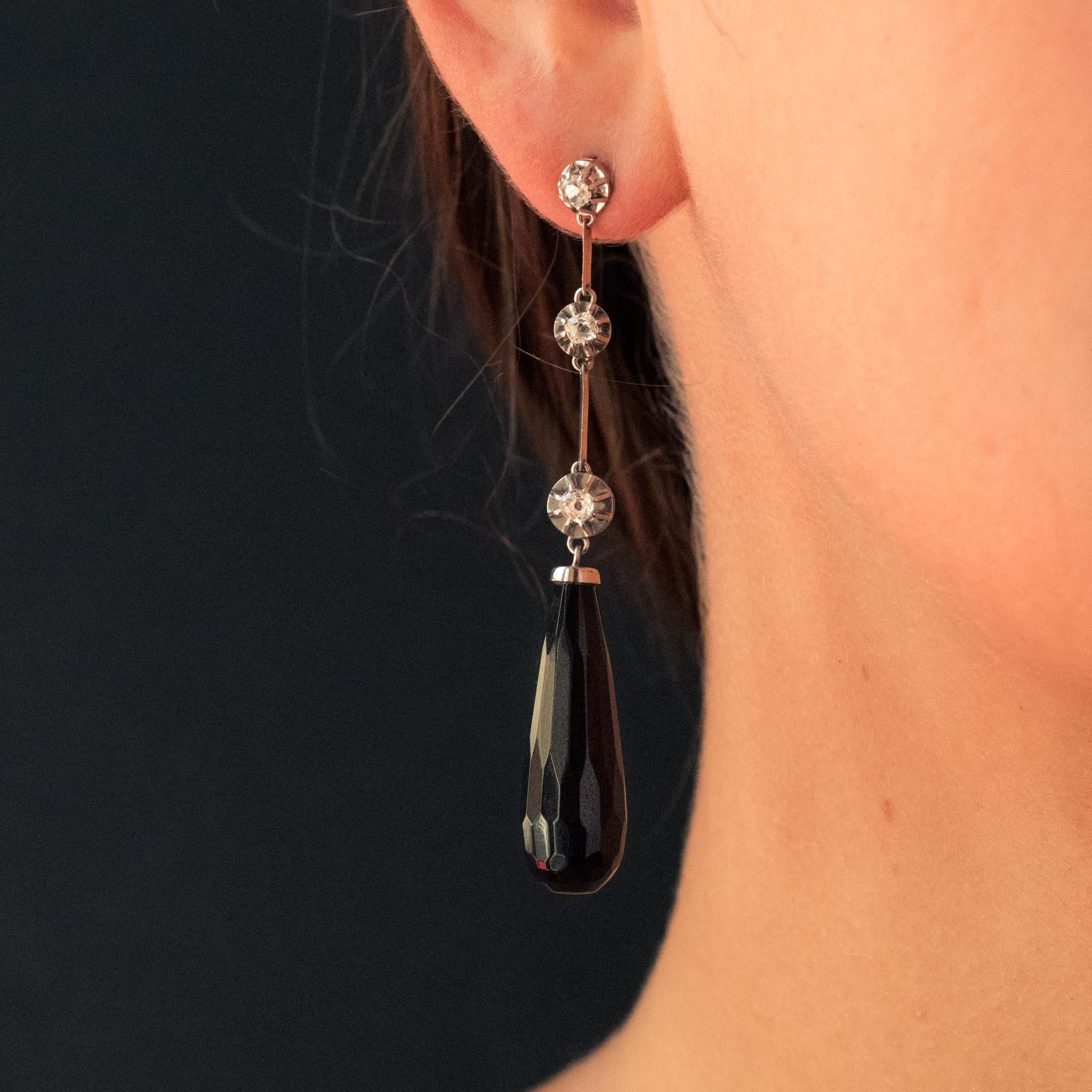Earring in platinum and 18 karat white gold eagle's head hallmark.
Slender earrings, they are formed from a drop of 3 antique cushion-cut diamonds separated by knives, and set with claws. The all retains a droplet of faceted onyx as a pendant. The