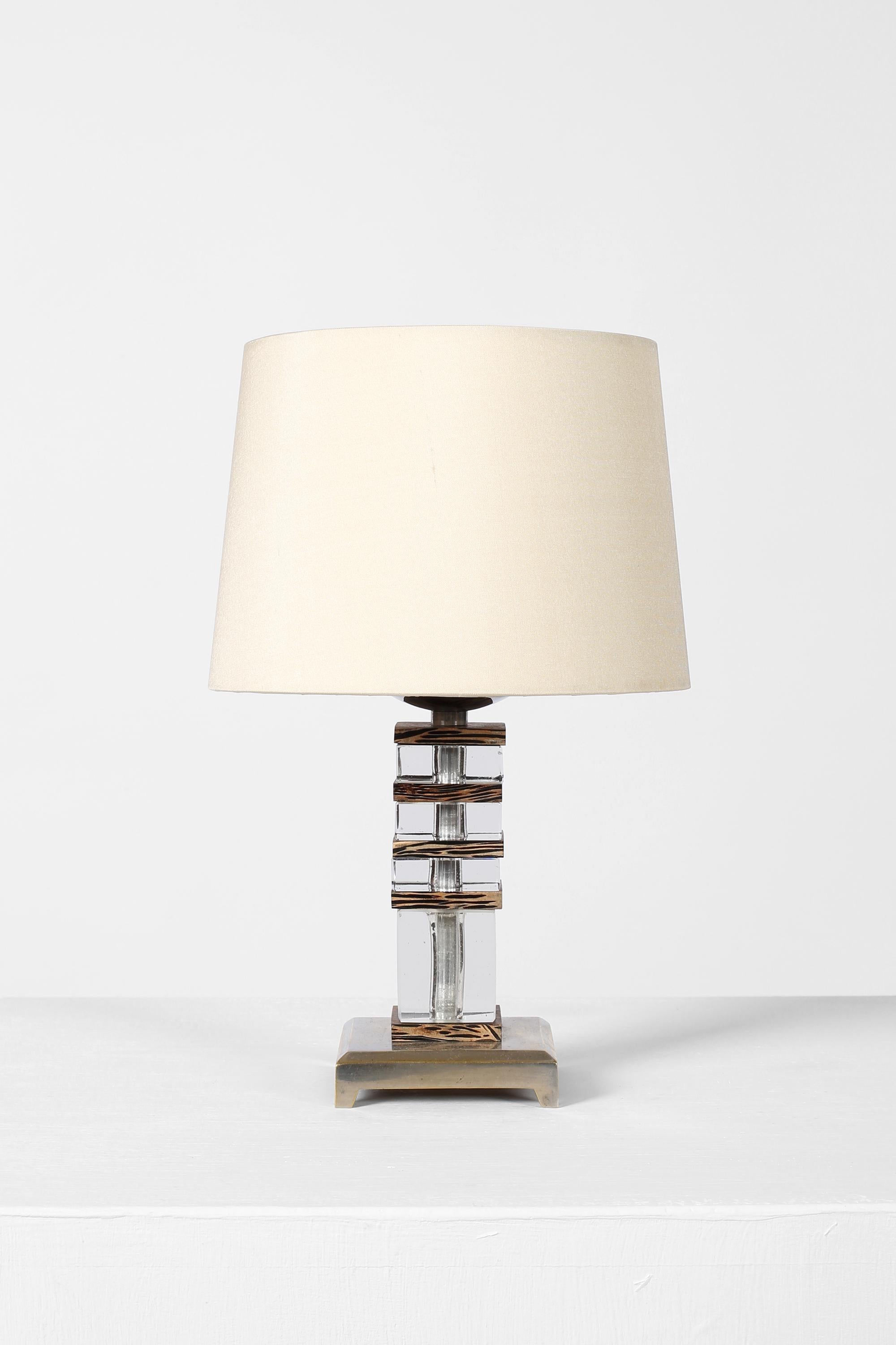 A chic and diminutive Art Deco table lamp in stacked cut glass and palm wood, with a nickel plated bronze base. French, c. 1930s. Supplied with a bespoke ivory dupion silk shade.