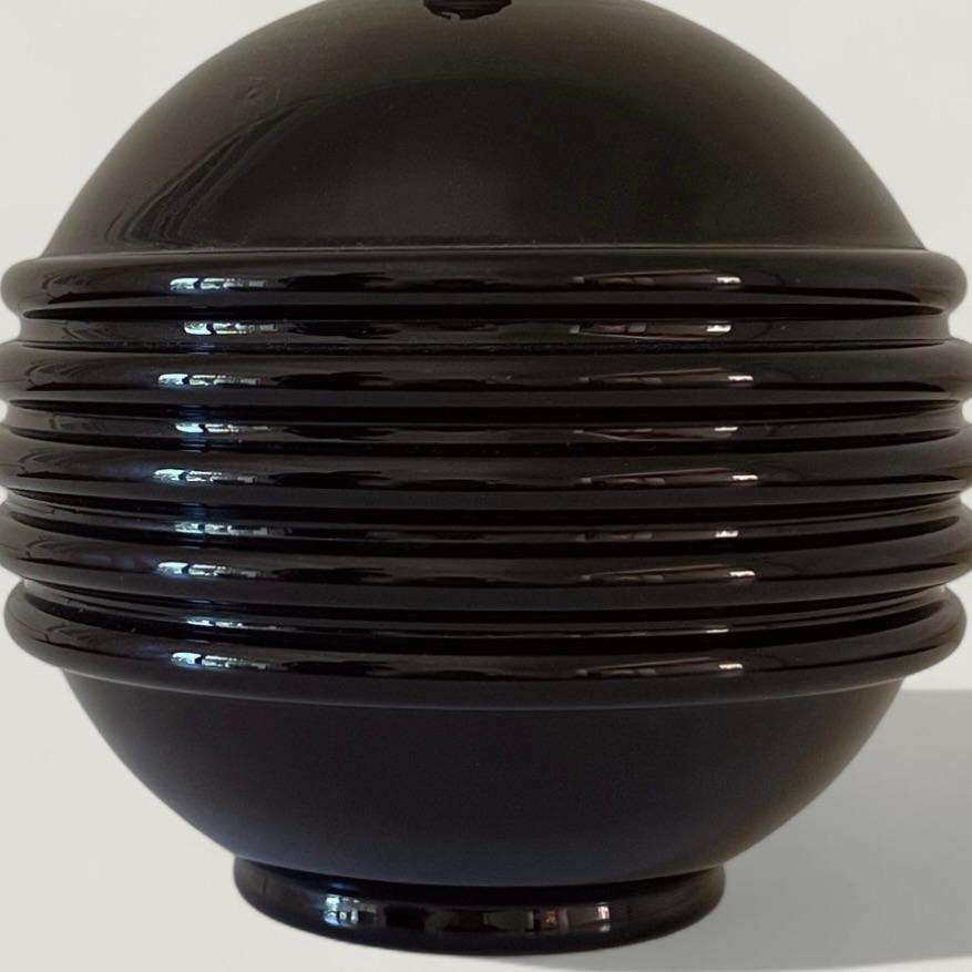 Magnifique lampe de table française en opaline noire attribuée à Jacques Adnet, avec une finition décorative nervurée et des ferrures en laiton patiné au niveau du col, vers 1930.
