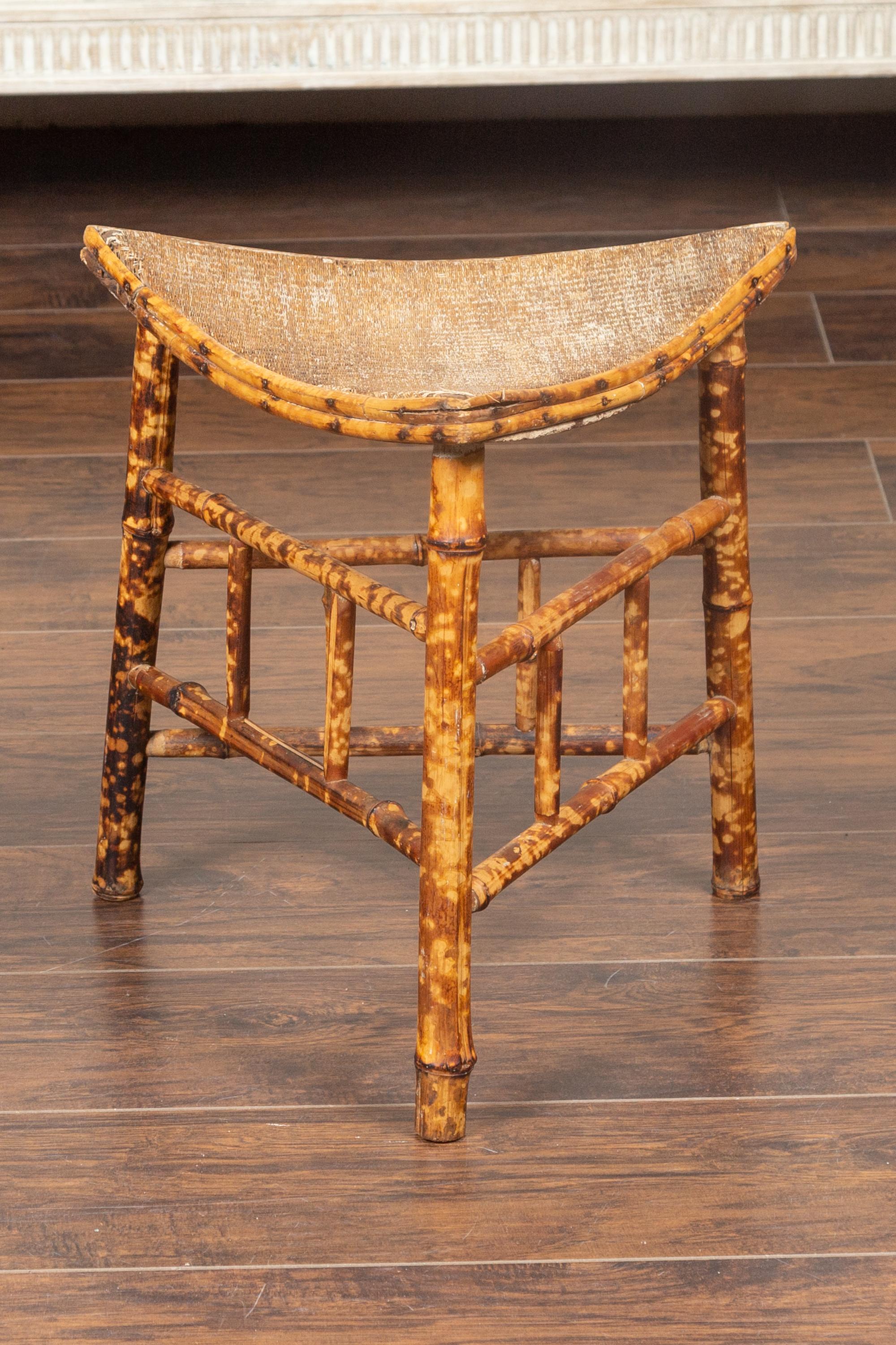 A French Egyptian Revival faux bamboo Thebes stool from the mid-20th century, with curving rattan seat. Born in France during the second quarter of the 20th century, this handsome Thebes stool features a triangular curving seat, resting on a stylish