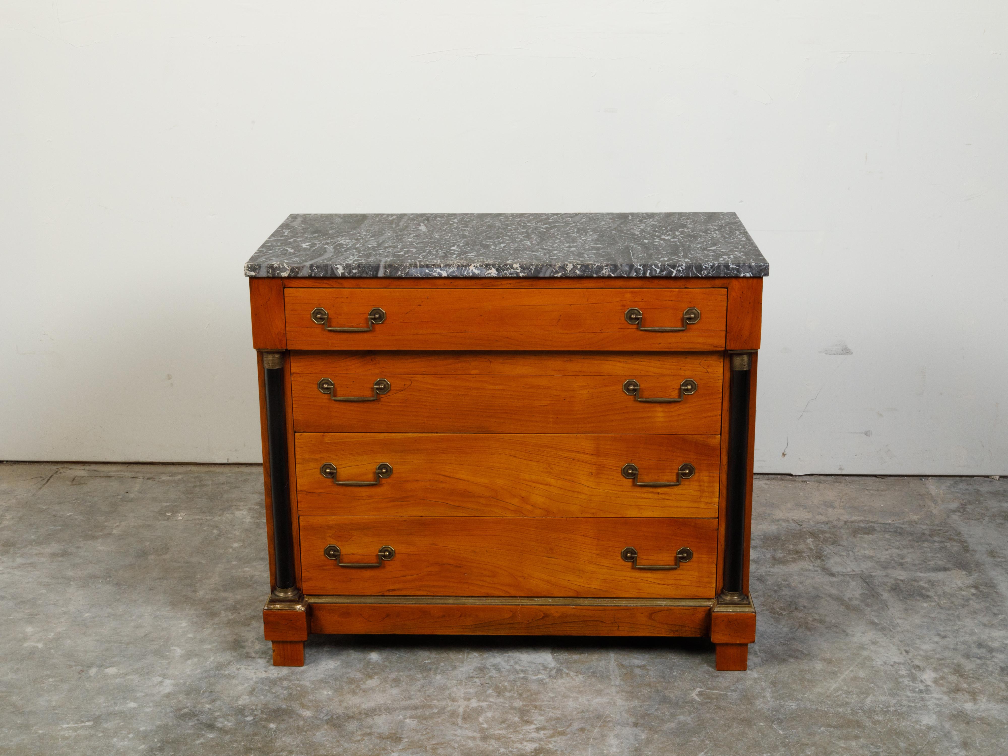 A French Empire style walnut commode from the early 20th century, with grey veined marble top four drawers and black columns. Created in France during the second quarter of the 20th century, this Empire style commode features a rectangular grey