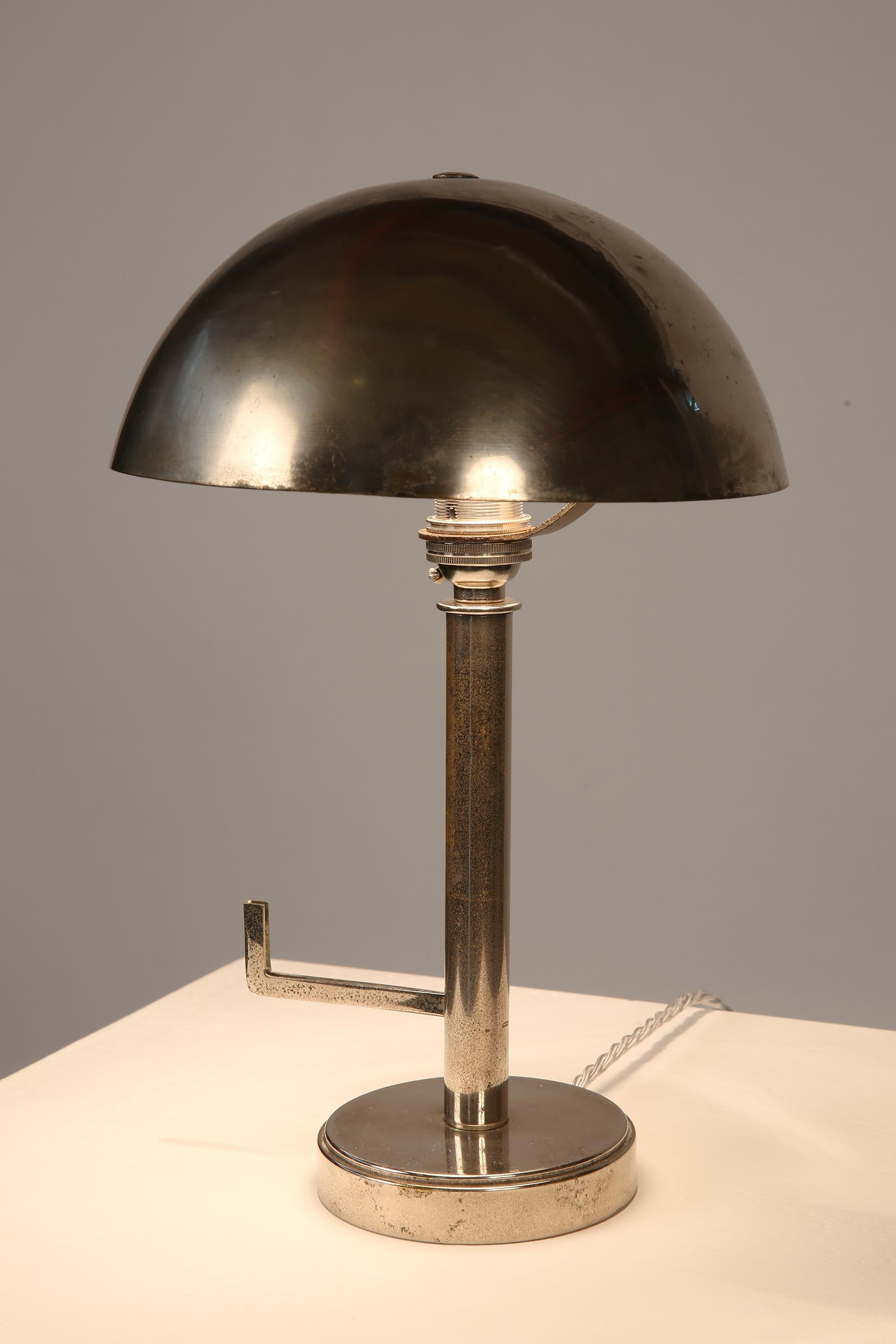 A modernist bedside lamp in nickel-plated brass, with simple dome shade and a unique angular ‘arm’ for hanging jewellery and/or watches.
