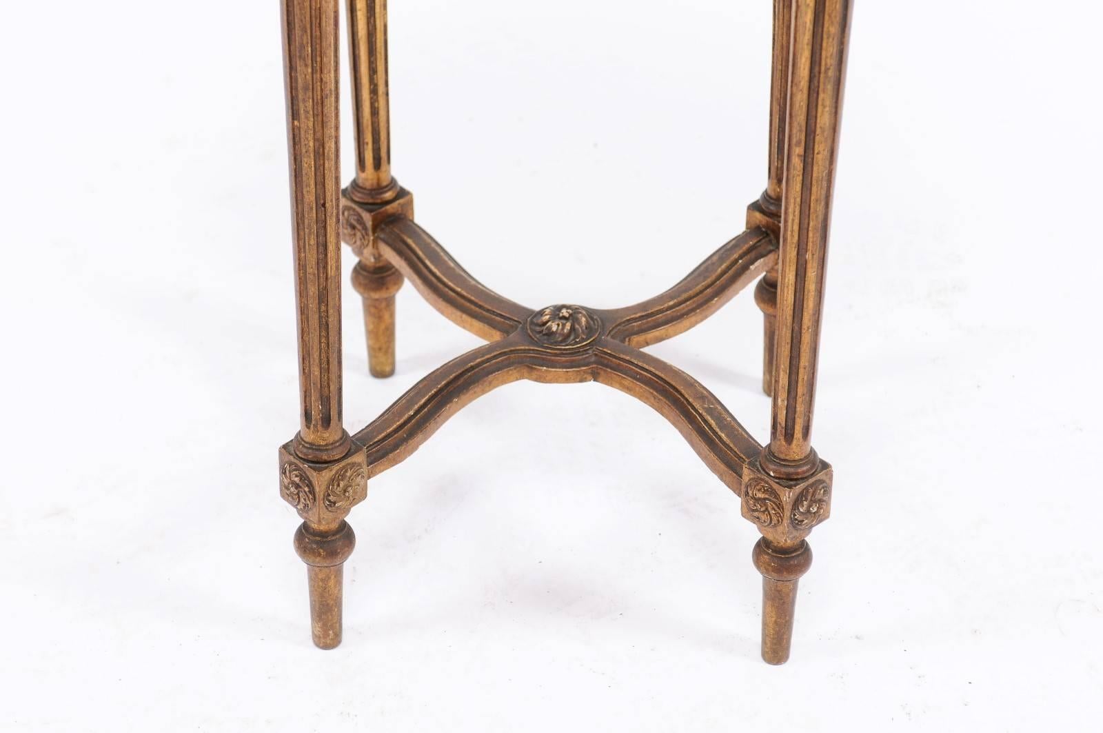 A French neoclassical style gilded wood guéridon table with variegated marble top, fluted legs and X-form cross stretcher from the first half of the 20th century. This charming little gueridon table circa 1930 will be right at home anywhere in your