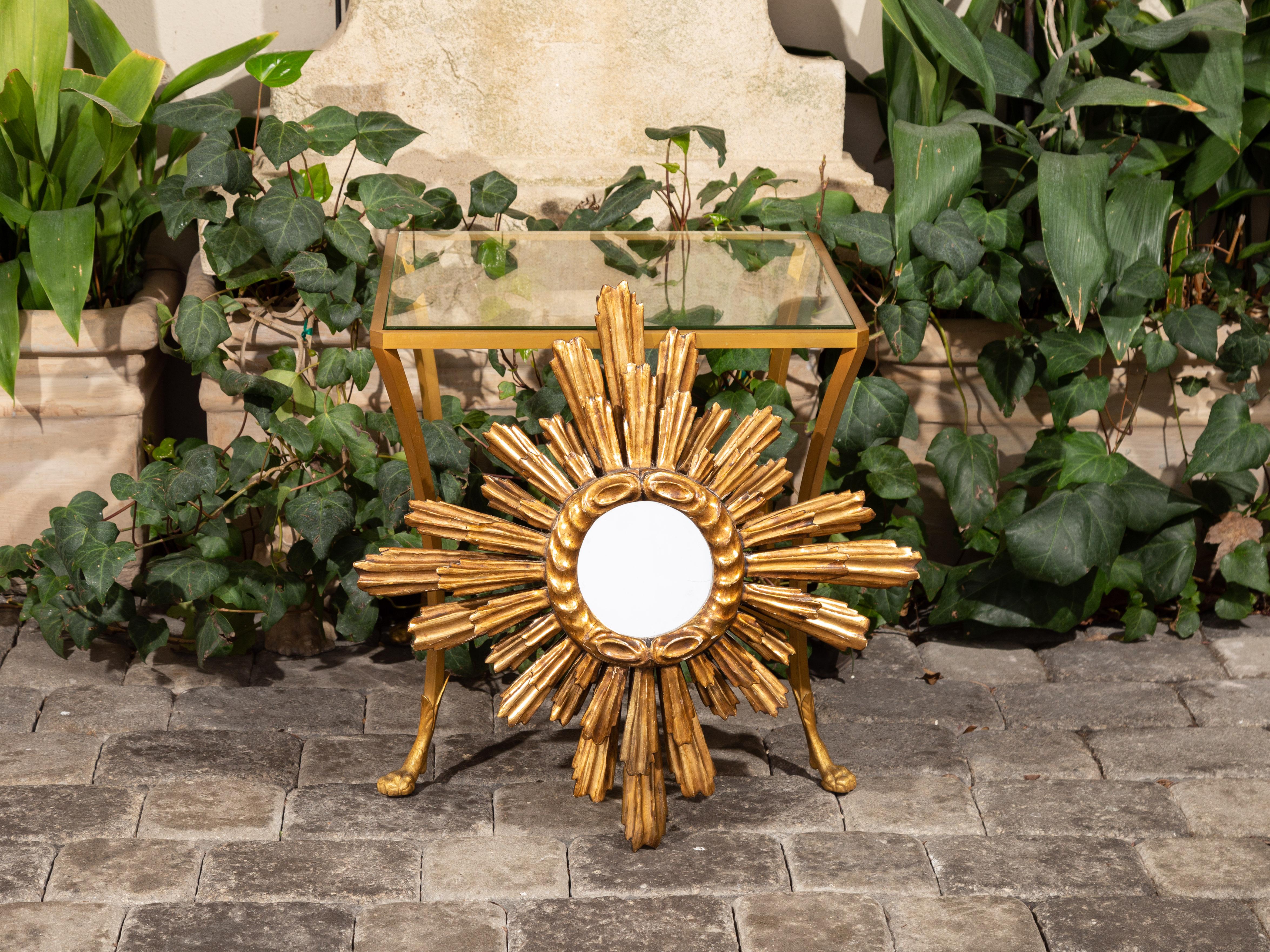 A French giltwood sunburst mirror from the early 20th century, with radiating two-layered rays and cloudy frame. Born in France during the second quarter of the 20th century, this sunburst mirror attracts our attention with its petite mirror plate