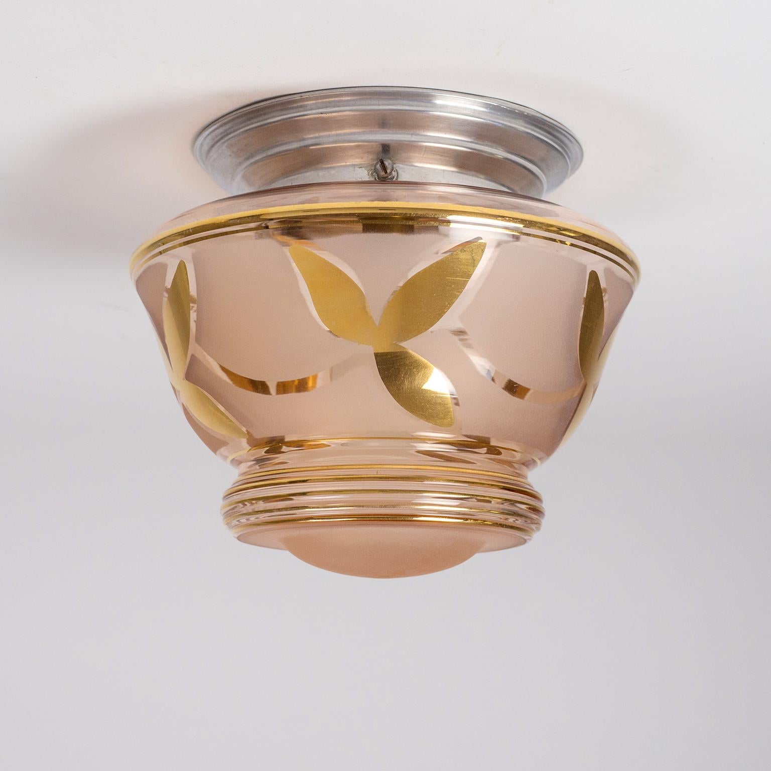 Charming French late Art Deco flush mount with a light Rosé colored glass. The lightly tinted and tiered glass diffuser has an abstract floral decor in gold paint and partial frostings. Very good original condition with barely any usage signs on the
