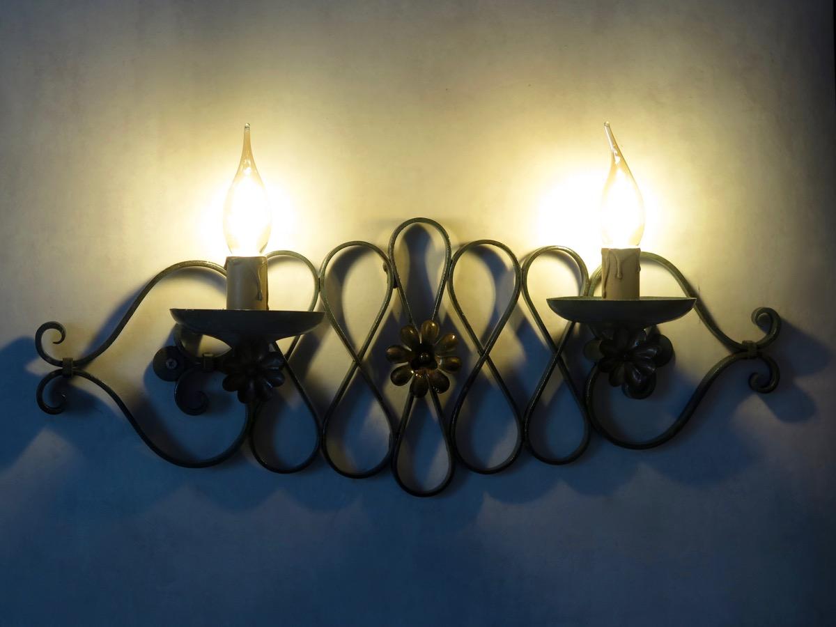 French 1940s Art Deco wrought iron wall lights, with a curlicued motif, each sconce holding two lights. The ironwork is painted in a matte sea green color, very typical of the era, with the rosettes picked out in gold-colored paint. Six available.