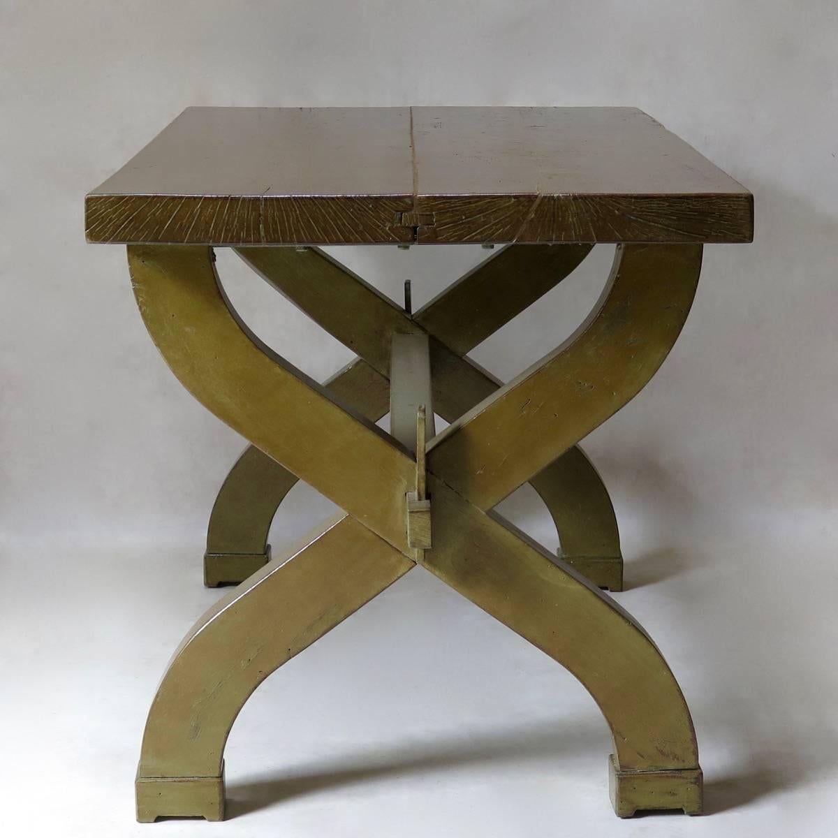 French Art Deco table of chunky proportions with a thick top, raised on a curule base, joined by a stretcher. Varnished finish.