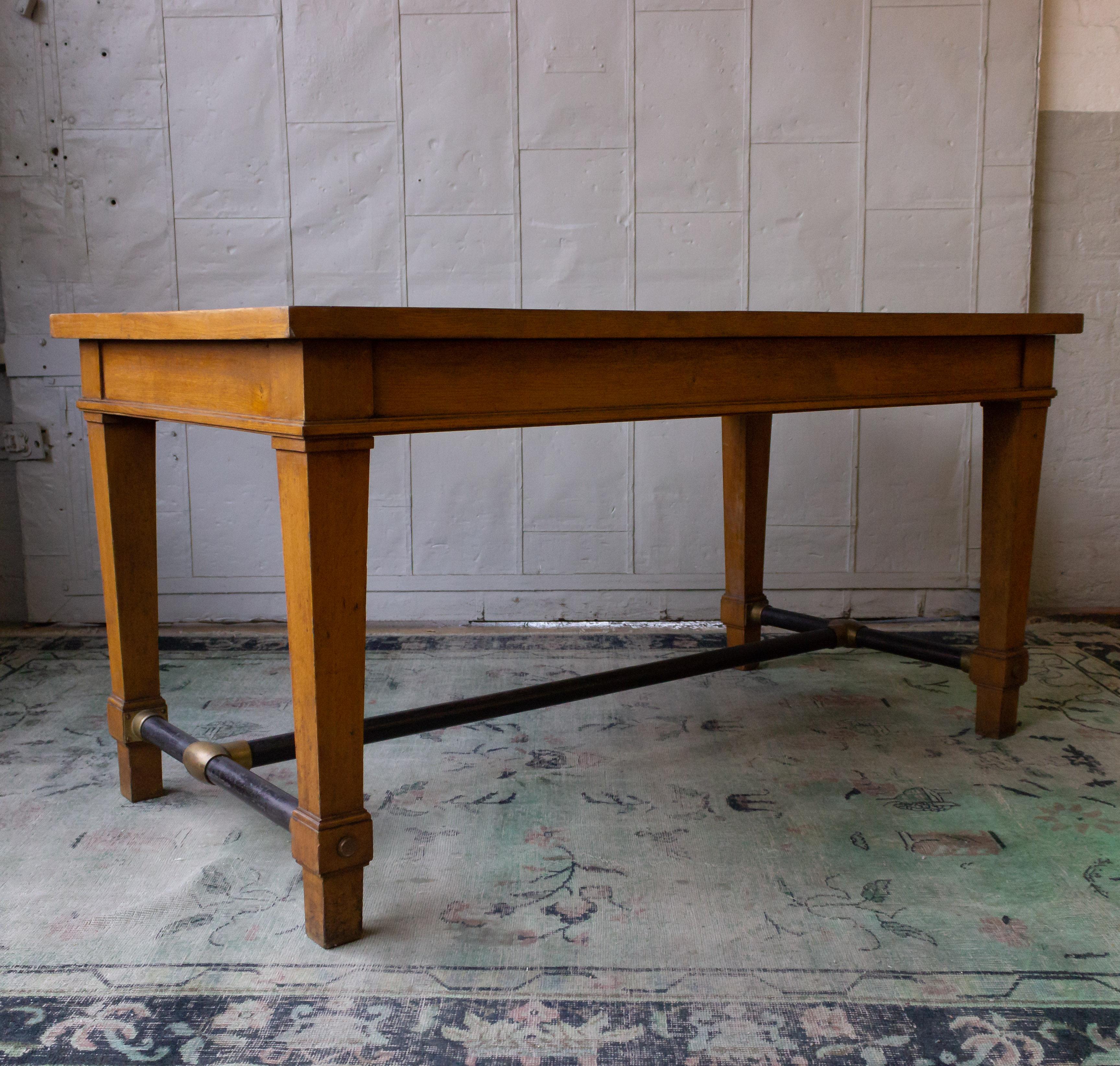 An unusual work table originally from the Banque de France, the natural colored wood has traces of hand painted black trim on the tops as well as on the moldings. The table has an iron and brass stretcher.  
Sold as is.

 