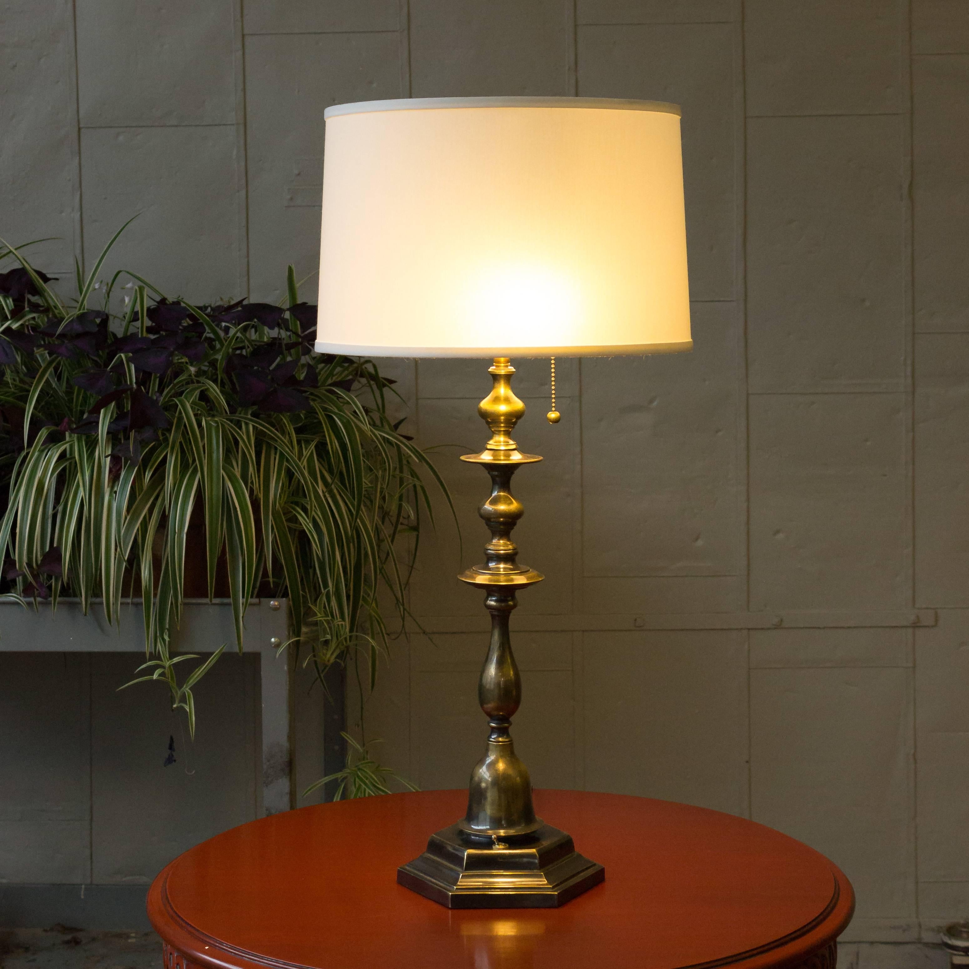 Recently refinished brass table lamp with turned and cast bronze parts. The hand finished finish shows variations in the patina to bring out the age of the piece. The lamps has been rewired with a black silk cord and a double light cluster, shade
