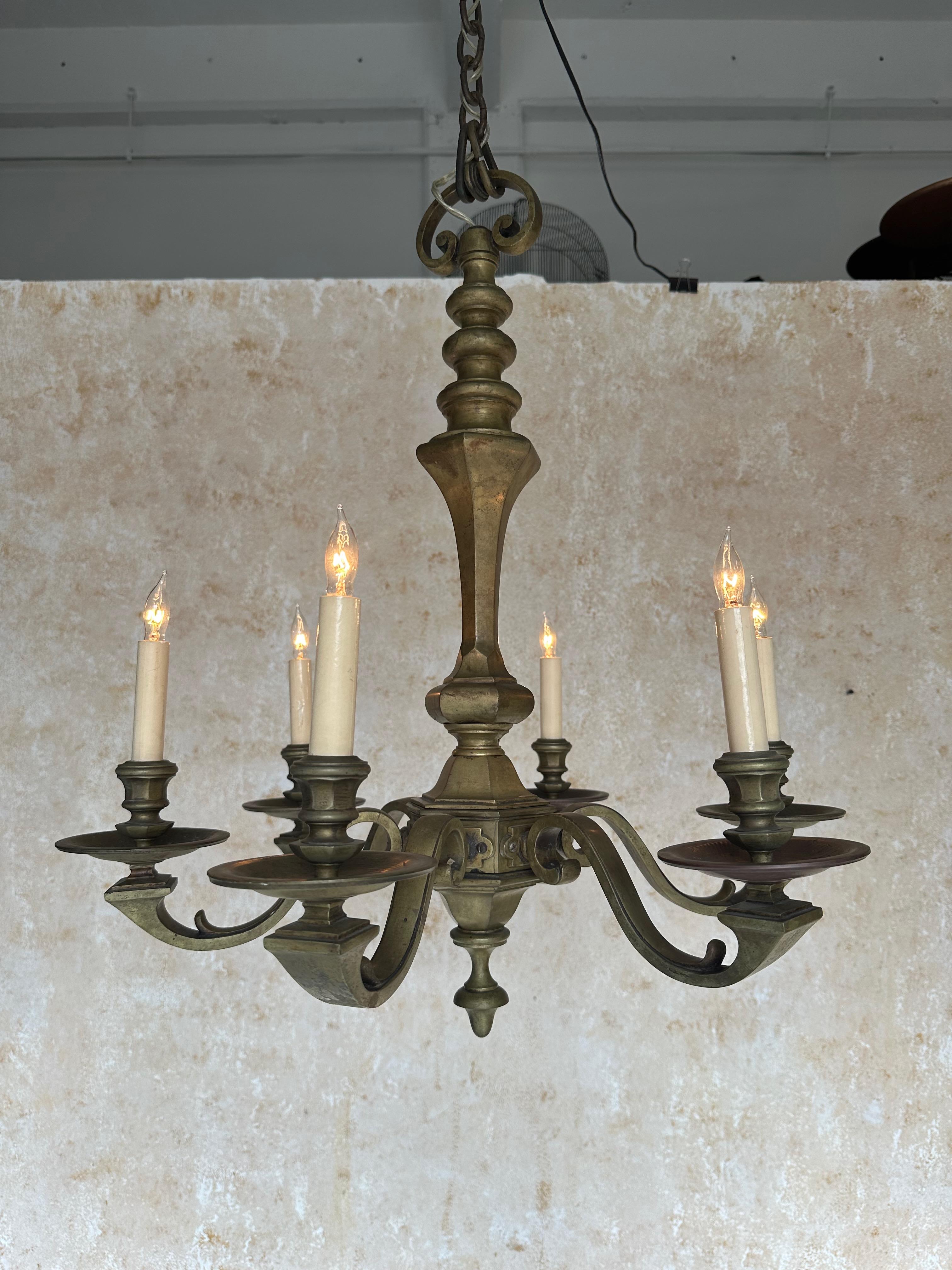 Una scala ridotta  Lampadario in ottone e bronzo in stile neoclassico francese degli anni '40 con sei bracci. La qualità di questo pezzo è evidente nella sua costruzione robusta e nei suoi dettagli intricati. Il lampadario è stato lucidato a mano