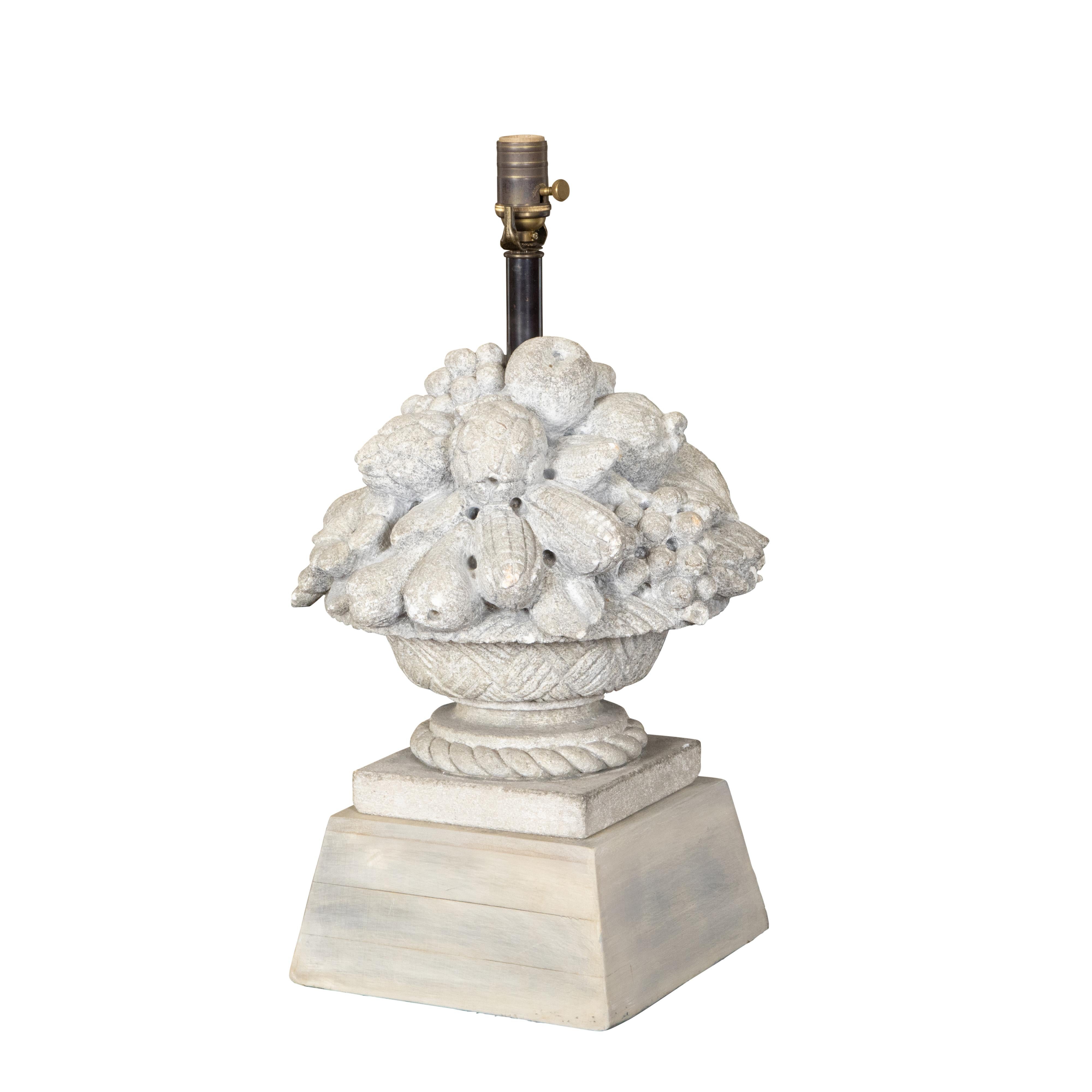 A French carved stone table lamp from the Mid-20th Century, depicting a fruit bowl on a tall pedestal, wired for the USA. Created in France during the second quarter of the 20th century, this table lamp features a carved stone body depicting a