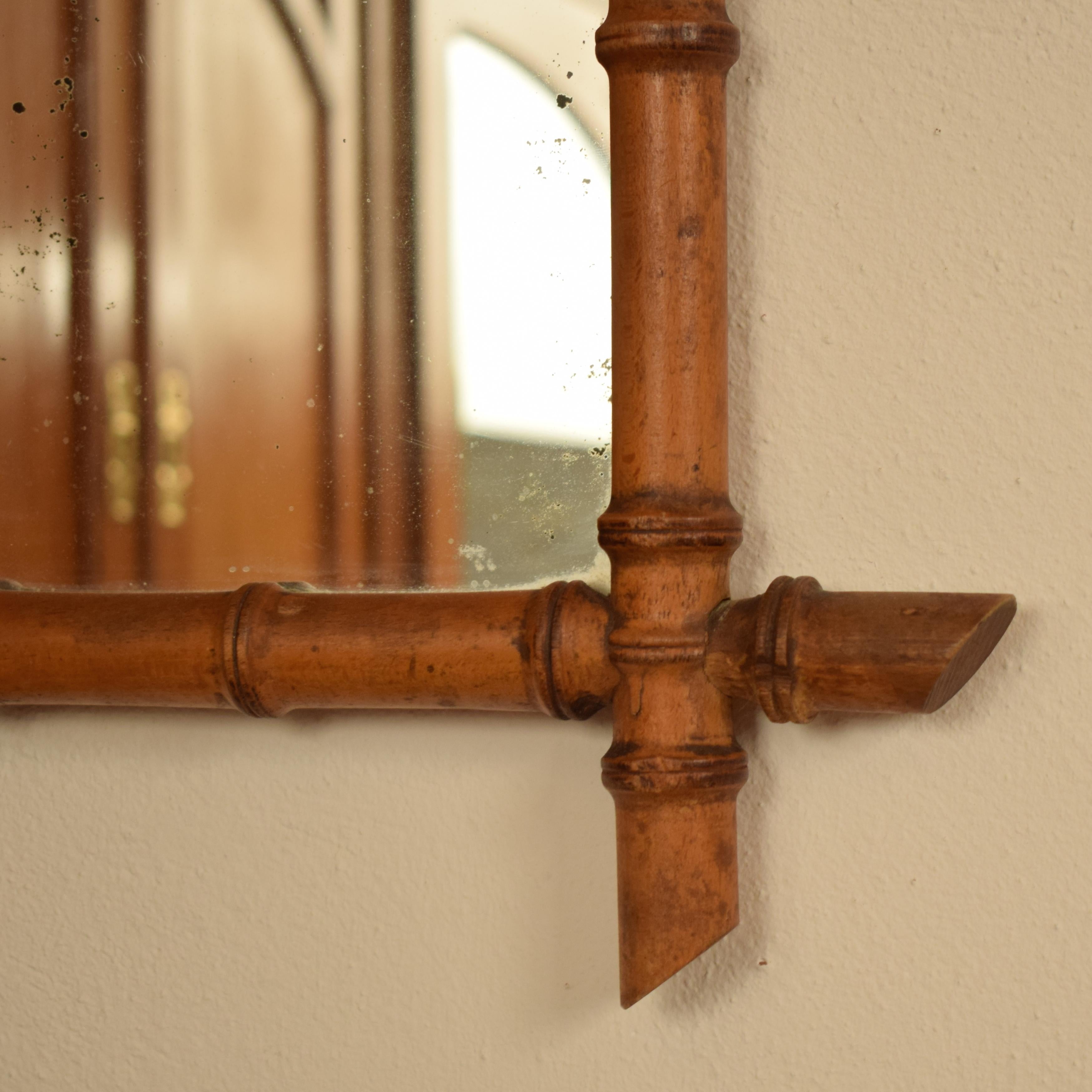 This French 1940s Colonial style faux-bamboo mirror contains its original glass and has a great patina.