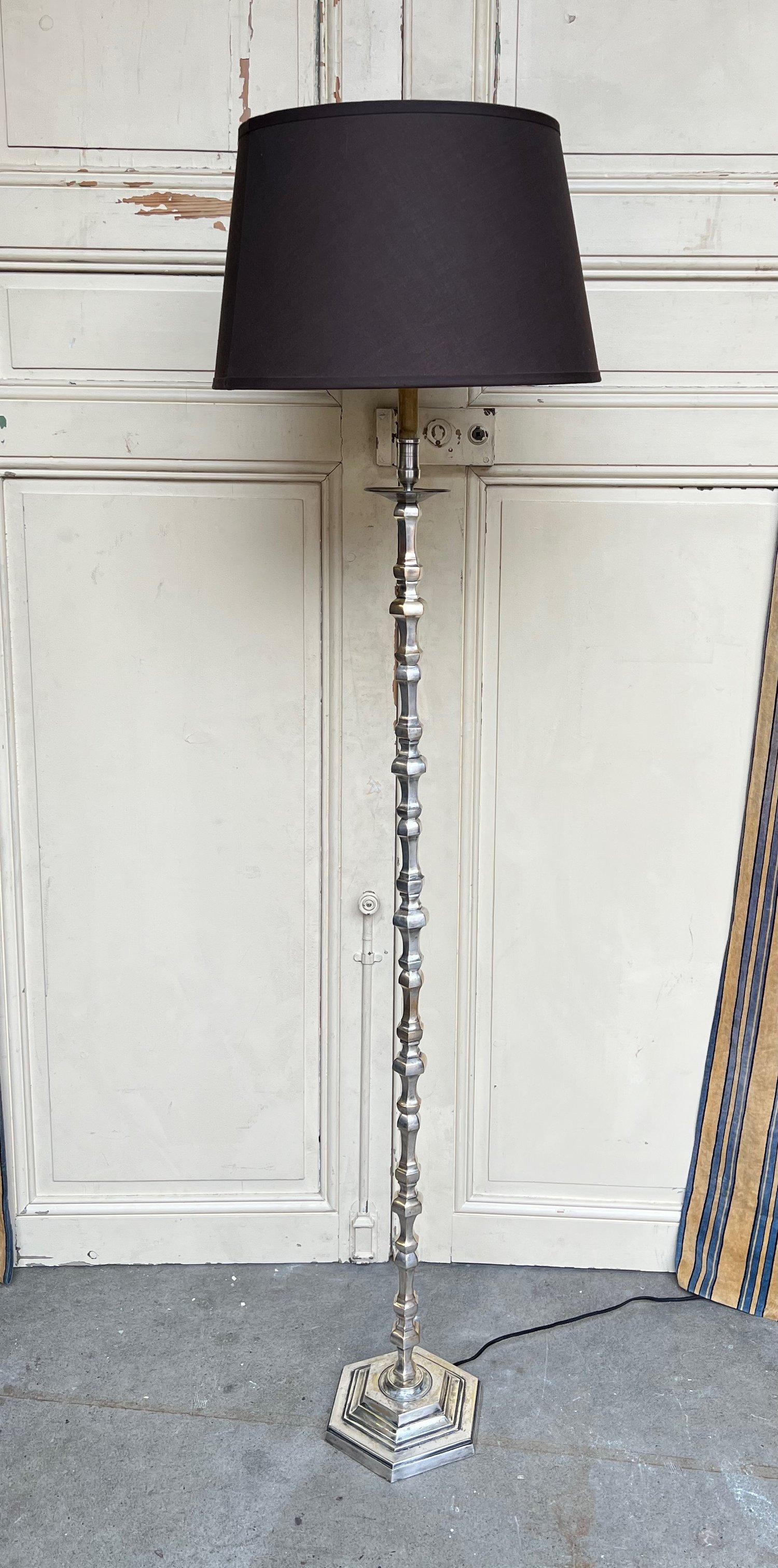 A handsome French floor lamp from the 1940s, made of silver plated brass and bronze. The lamp stands on a hexagonal base, supporting a captivating arrangement of turned pieces in various sizes. These elements create a visually engaging pattern that