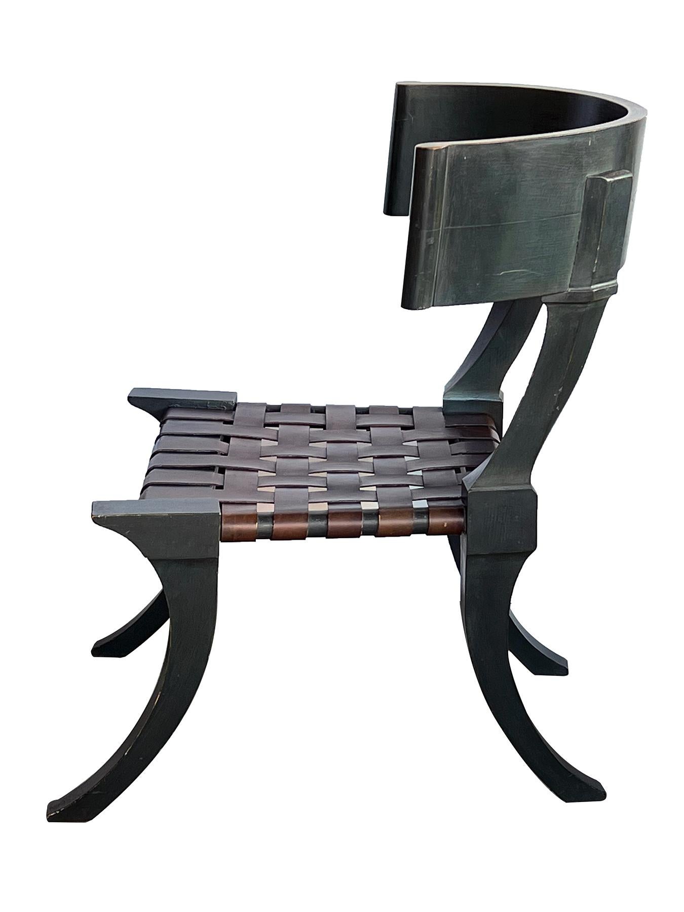Une chaise Klismos française des années 1940, de grande taille et de conception élégante, avec un dossier incurvé profond avec des terminaisons en volute ; au-dessus d'un siège en cuir avec des sangles entrecroisées, le tout reposant sur des