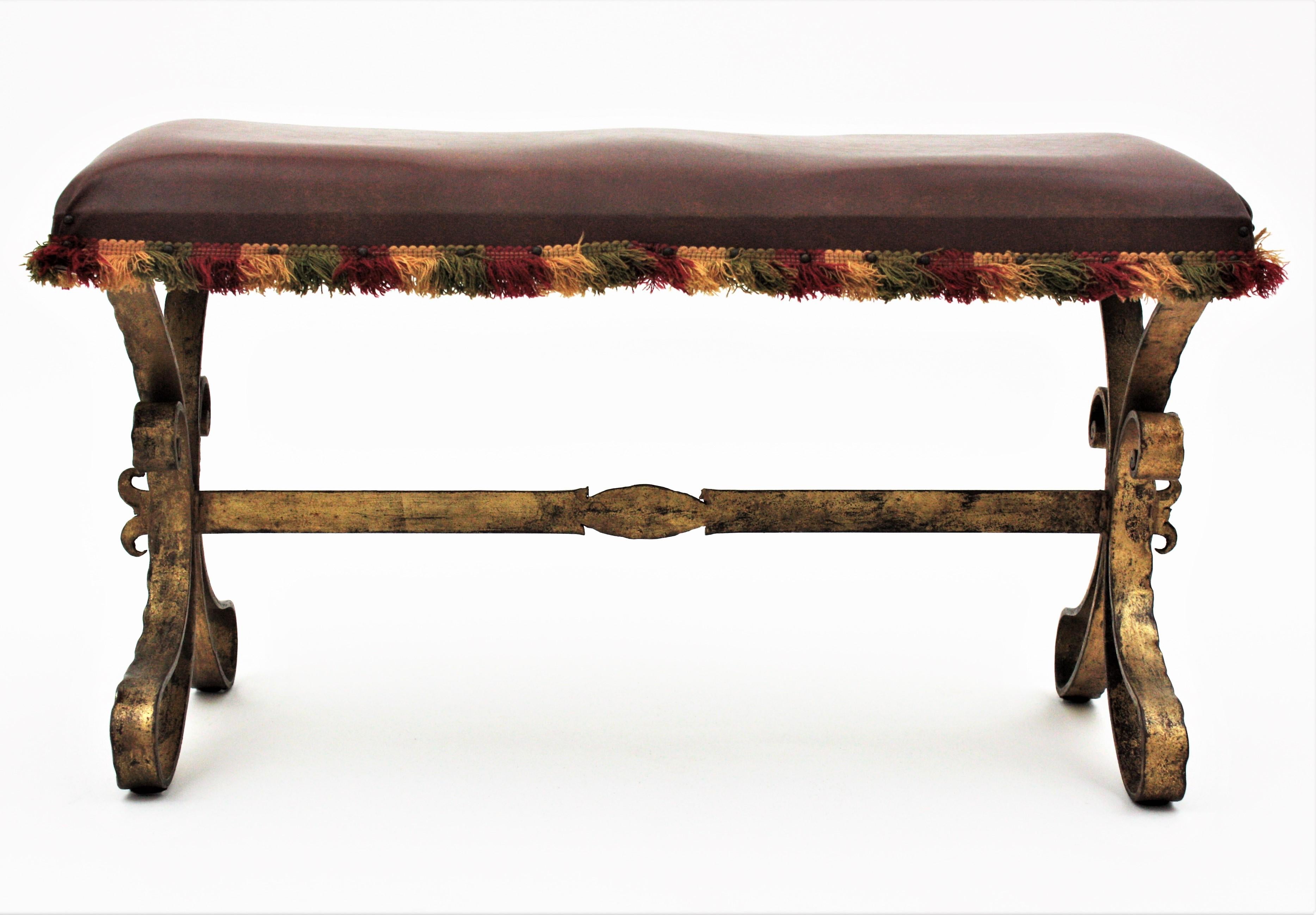 Stylish Neo-Baroque hand-hammered iron bench with looped feet in the style of Gilbert Poillerat, France, 1940s.
This bench has a seat with its original vintage fringed upholstery. It stands on a four-footed hand forged iron base and each foot has