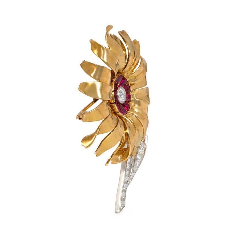 A Retro gold flower brooch centering on a ruby and diamond pistil, with a diamond stem and leaf accented with rubies on the underside, in 18k and platinum.  France.   Atw center diamond 0.56 ct.  Atw diamonds in stem and leaf 1.10 ct.