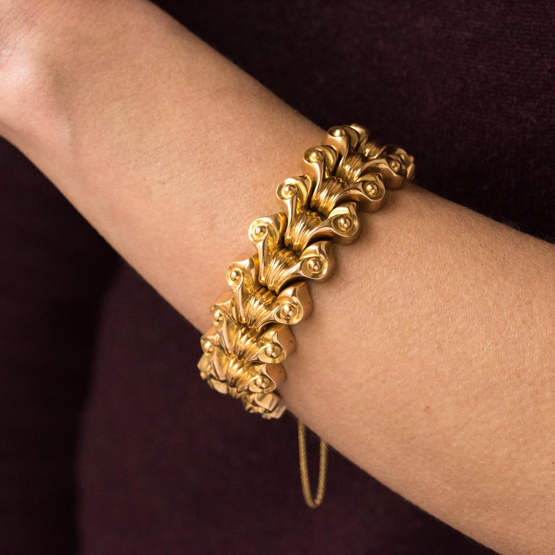 Bracelet en or jaune 18 carats, poinçon tête d'aigle. 
Composé de 17 motifs de volutes, avec un décor de lignes et de perles dorées, reliés entre eux. Le fermoir est un cliquet en forme de 8 avec une chaîne de sécurité. 
Diamètre intérieur : 5,5 cm,