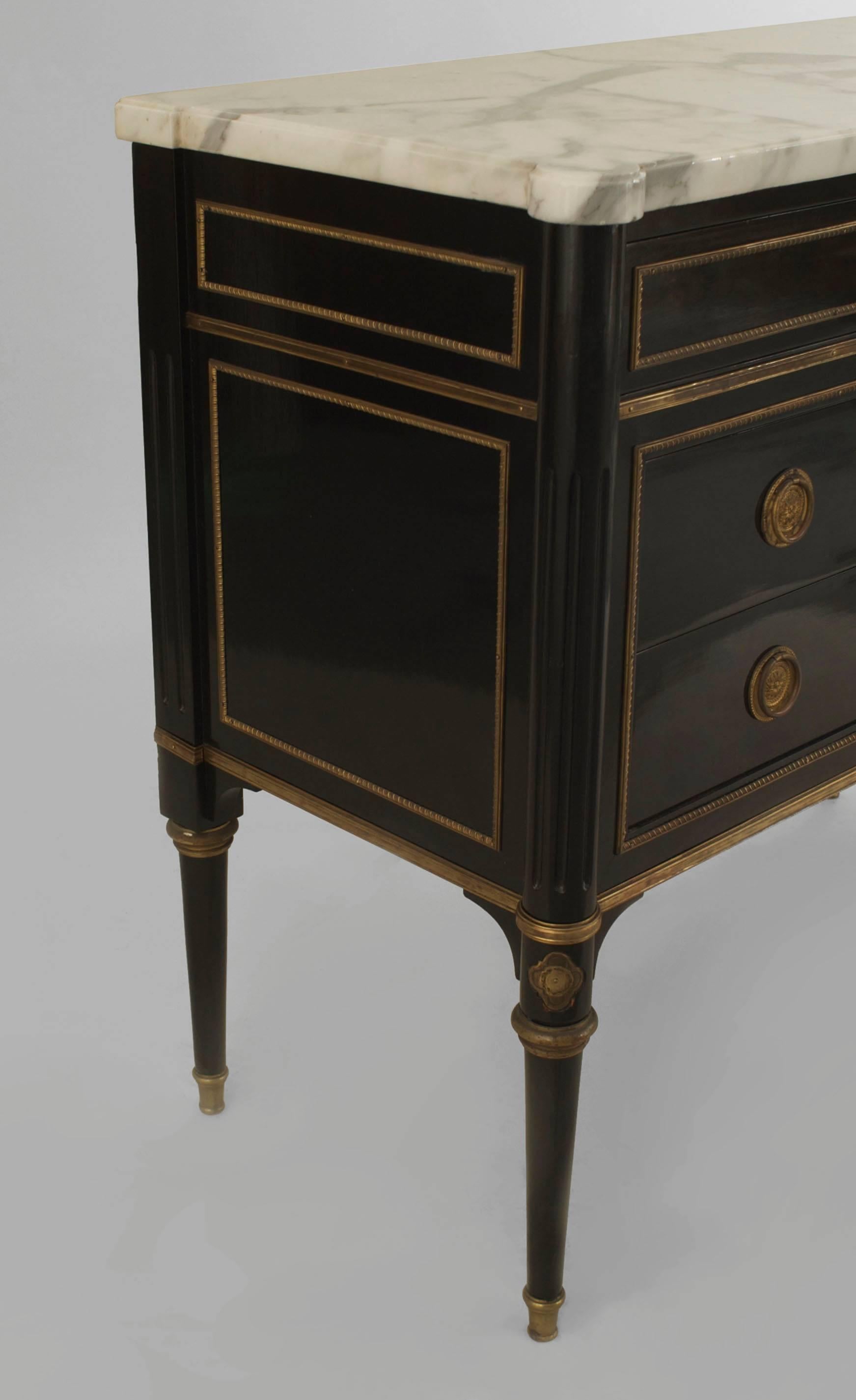 French 1940s (Louis XVI style) ebonized commode with bronze trim and having a single top draw over two larger drawers with bronze round handles with a white marble top (stamped JANSEN).

 