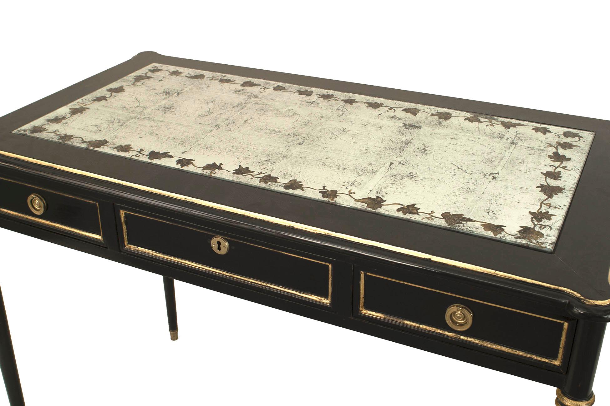 French Louis XVI style (1940s) ebonized and gilt and bronze trimmed table desk with 3 drawers and an inset √©glomis√© mirrored top with floral decoration (stamped: JANSEN)
