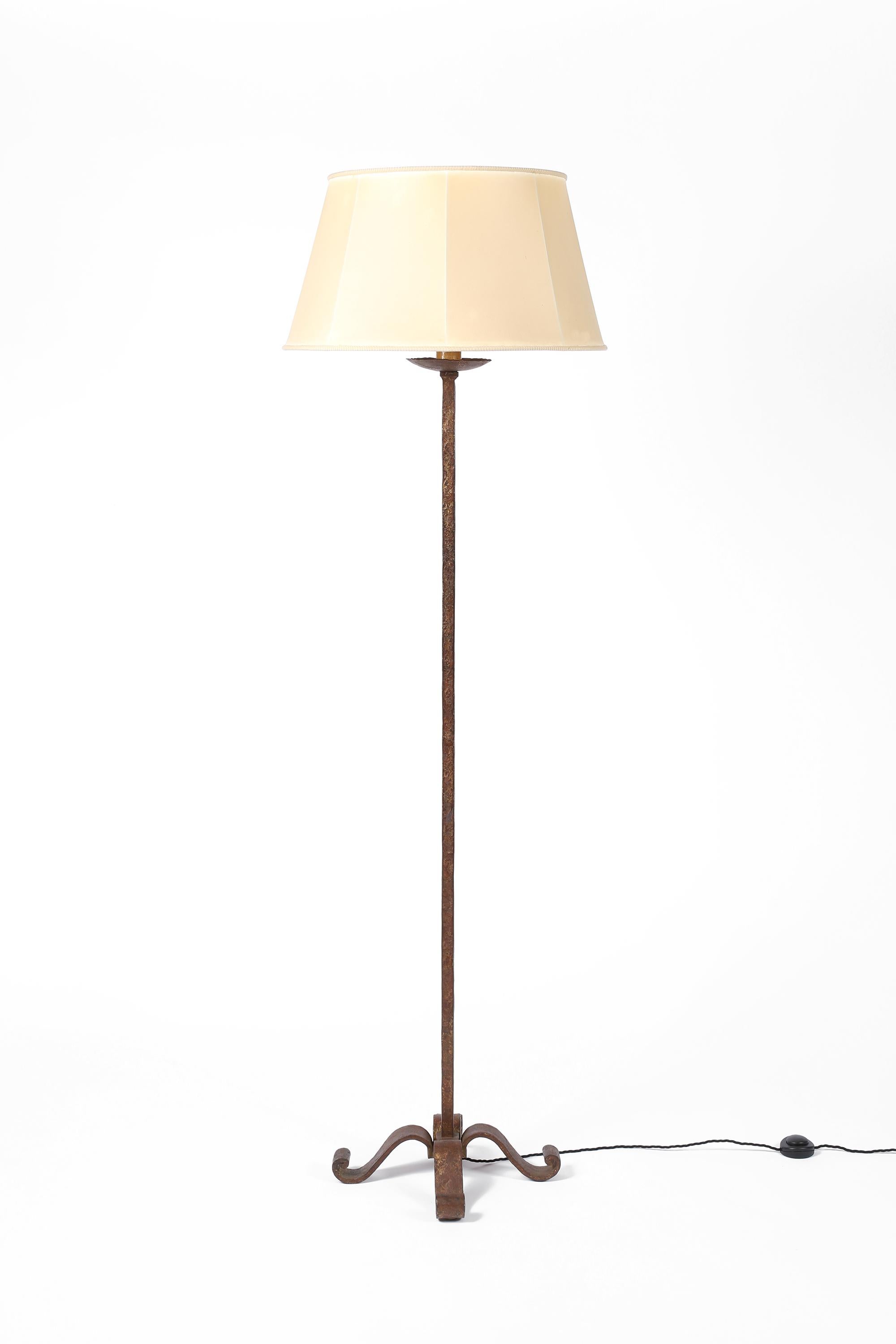 A chic, large forged iron floor lamp with simple stem and decorative scrolled base by Maison Ramsay - Paris. Beautifully patinated with visible remnants of the original gilt finish, the lamp retains its original vellum shade in superb condition.
