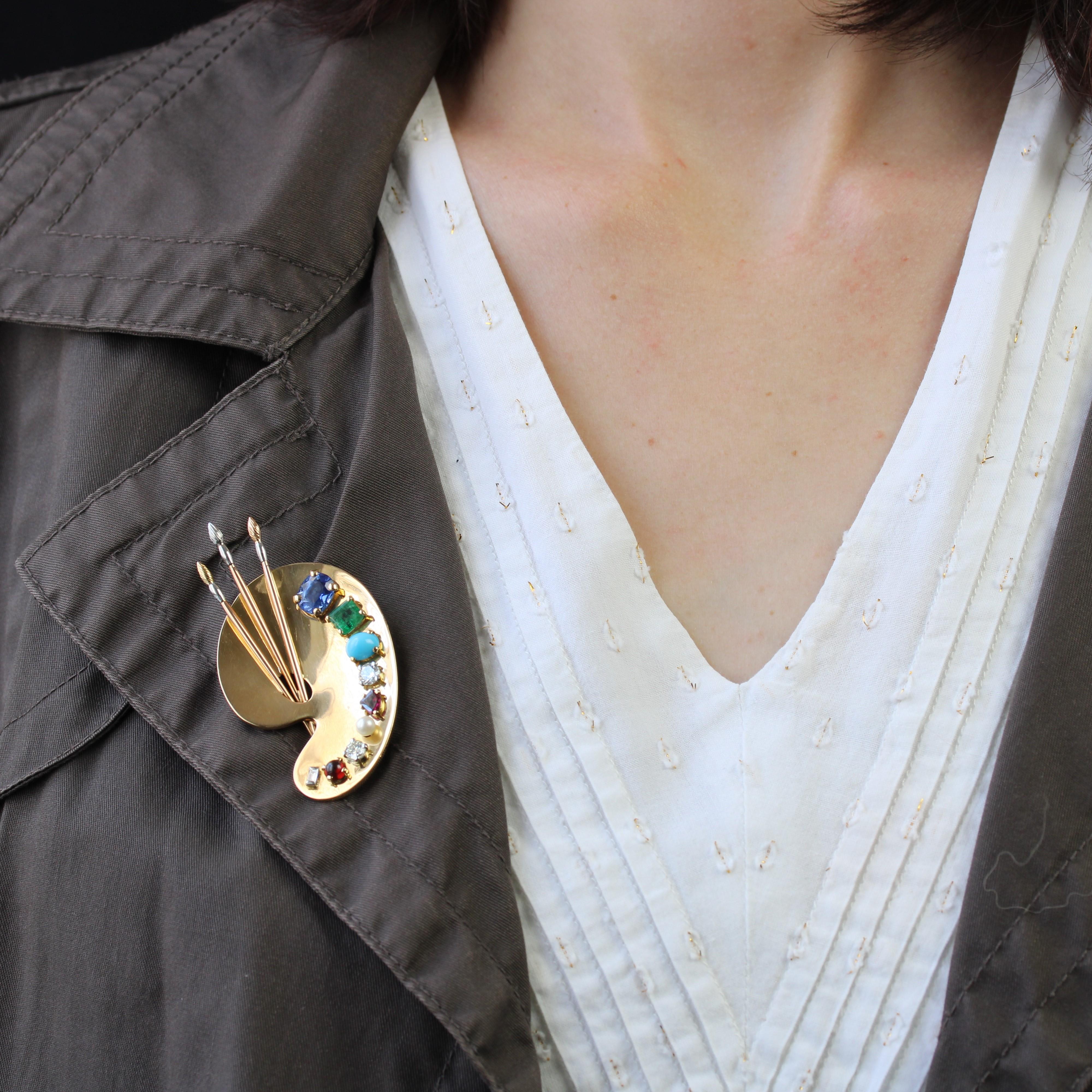 Brooch in 18 karat yellow and rose gold, eagle head hallmark and platinum, dog's head hallmark.
An astonishing brooch in the shape of a painter's palette, it features a smooth gold plate, pierced and appliquéd with 3 brushes in rose gold and