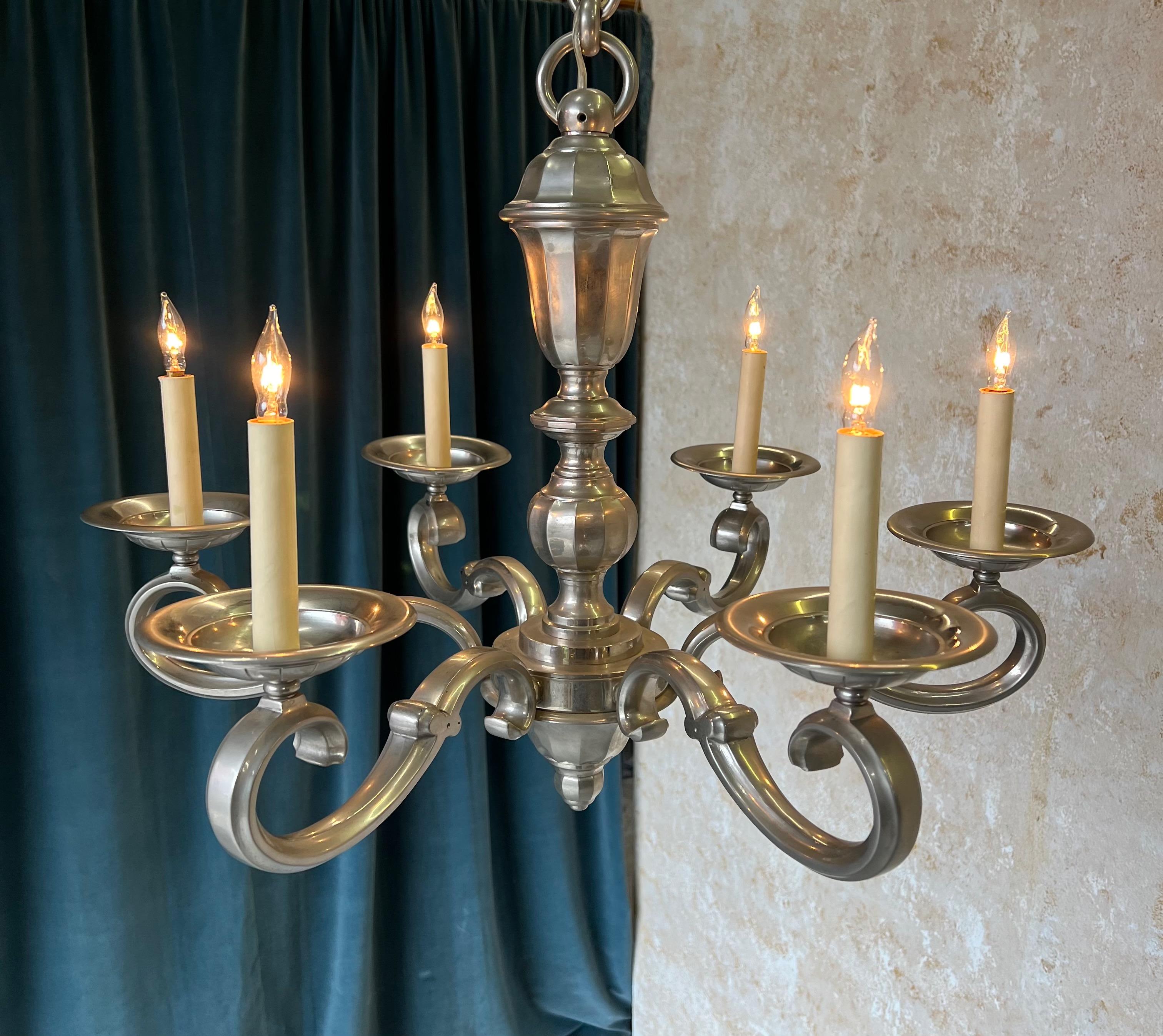 Questo elegante lampadario francese del 1940 in bronzo nichelato a sei braccia emana un'aura di raffinatezza e grazia. Questo pezzo senza tempo comprende una catena e un baldacchino coordinati, che ne aumentano il fascino. Recentemente ricablata,