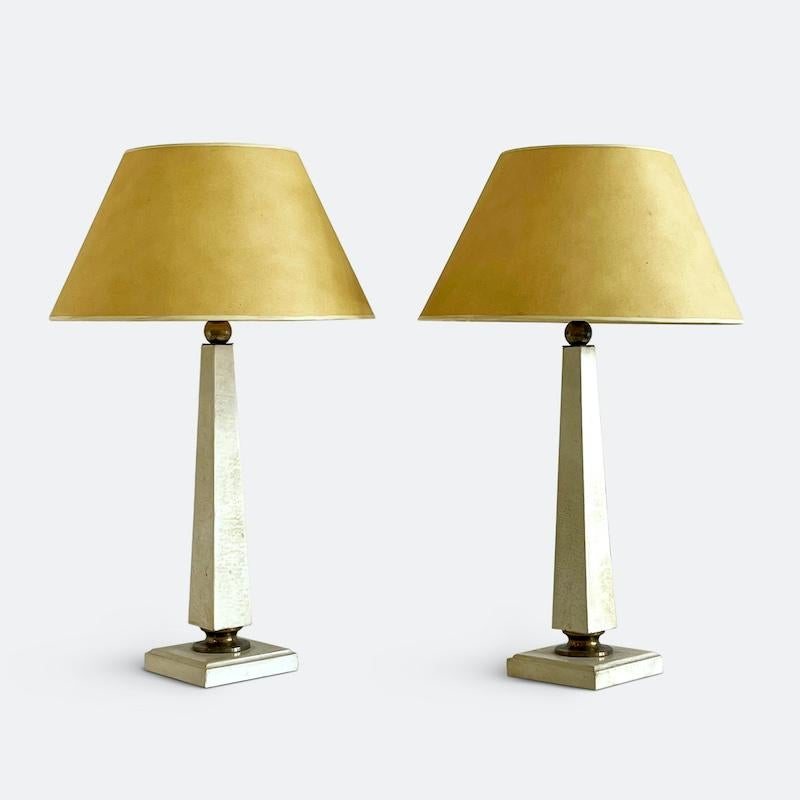 An elegant pair of French table lamps from the 1940s attributed to Andre Arbus.
Of neoclassical obelisk form on low square basses wrapped in parchment and finished with brass ball and upturned cup hardware. 

Provenance:
Marche Paul-Bert Serpette,