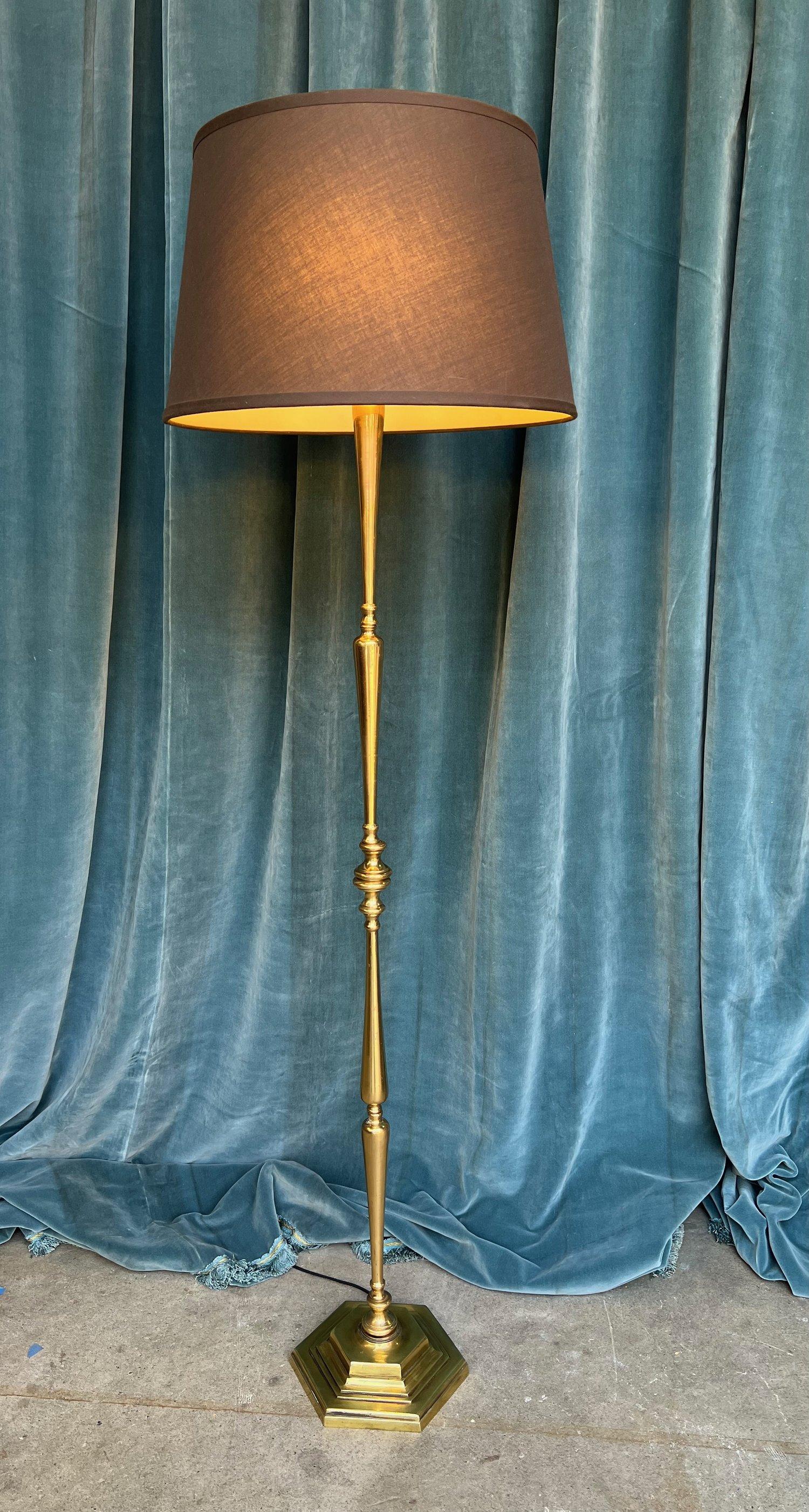 This elegant French floor lamp dates back to the 1940s, built from brass and bronze in a classic design. The lamp stands on a weighted, stepped-up hexagonal base, giving it a stable and sturdy foundation. Turned solid brass components are assembled