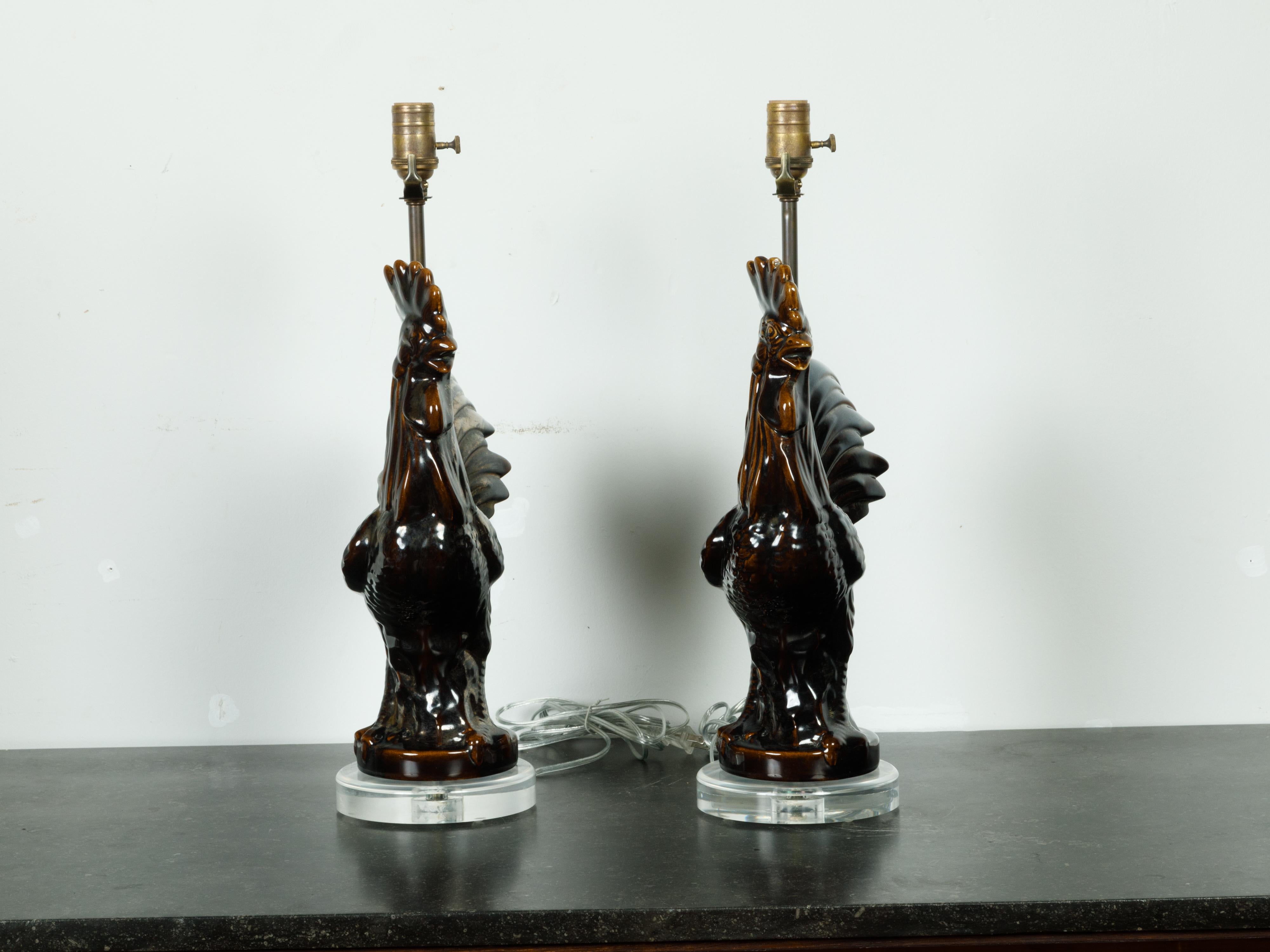 Two French pottery rooster table lamps from the mid 20th century, with dark patina and lucite bases, priced and sold individually $1,200 each. Created in France during the second quarter of the 20th century, each table lamp draws our attention with