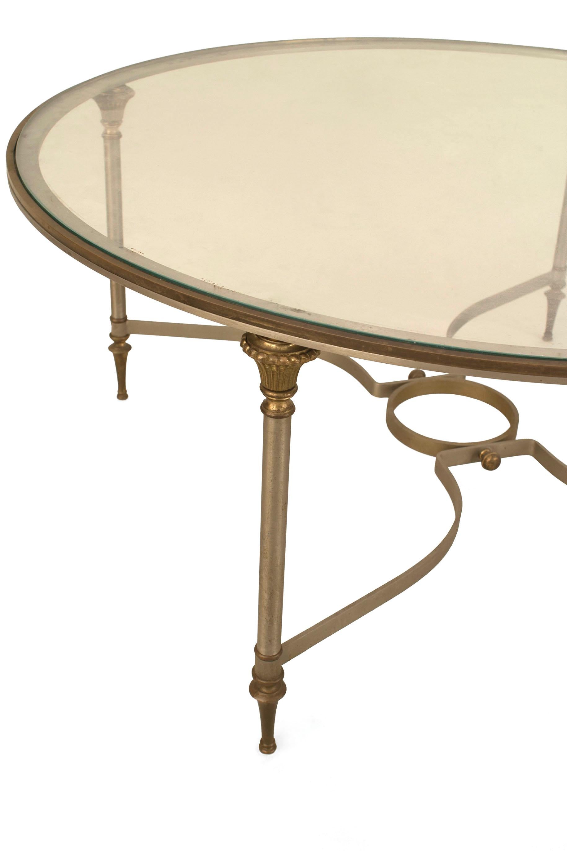 Modern French Mid-Century (1940s) round metal coffee table with 4 legs connected by a stretcher with a center ring and supporting a glass top. (stamped: MAISON JANSEN)
