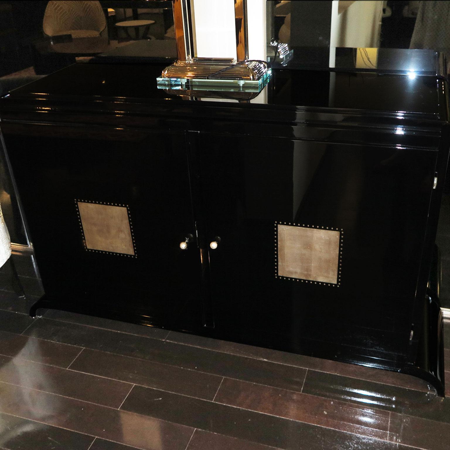 French, late Art Deco period sideboard in black lacquer with stepped plateau and curved base. Square detail in silver leaf on each door, with dotted embellishment surrounding each square.  Key knobs in silver leaf. Adjustable interior shelving.