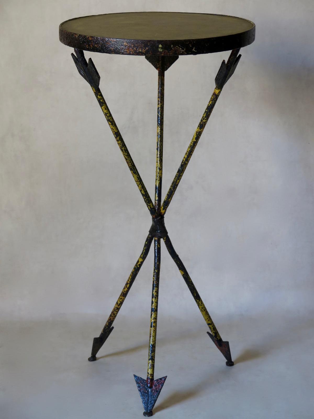 Elegant French Art Deco table from the 1940s, raised on a tripod base, with original red and yellow polychrome finish. The legs end in large arrowheads. Beige/grey resin top. The wrought iron has acquired a pleasant, pitted surface.
