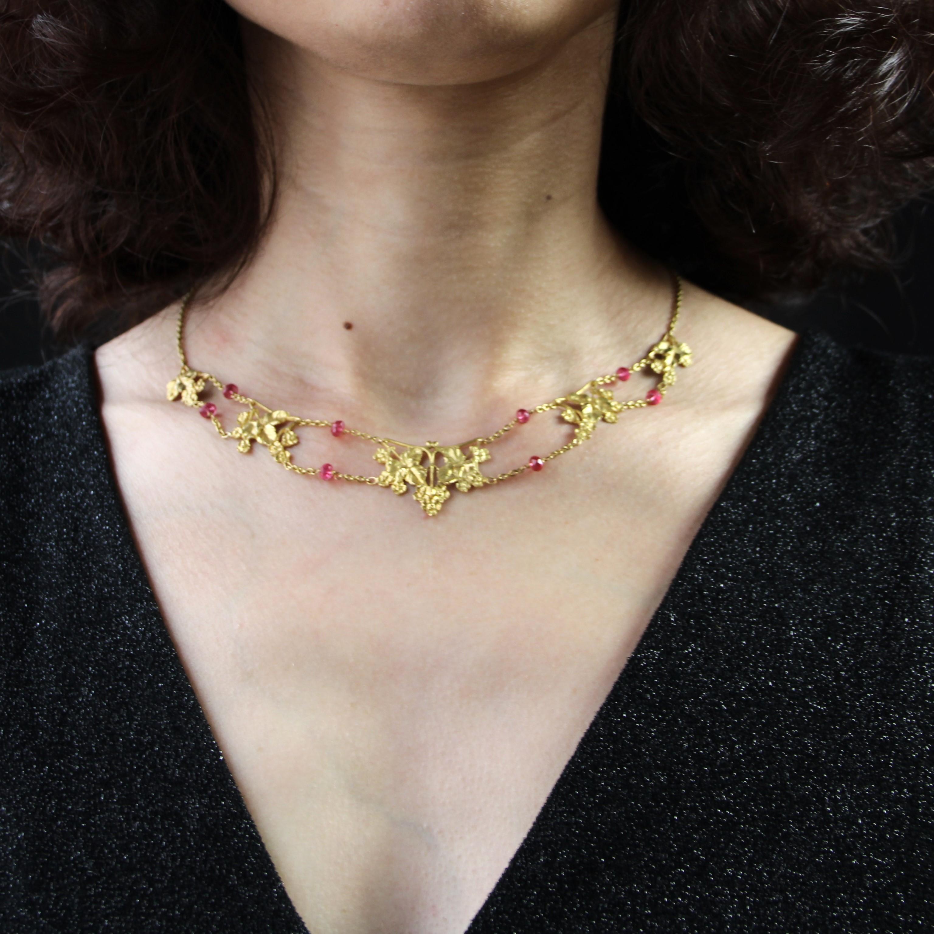 Halskette aus 18 Karat Gelbgold, Adlerkopfpunze.
Die schöne Golddrapierung besteht aus geschnitzten Efeublattmotiven, zwischen denen eine Doppelkette mit facettierten rosafarbenen Spinellperlen verläuft. Die Schließe ist ein Federring.
Gesamtlänge: