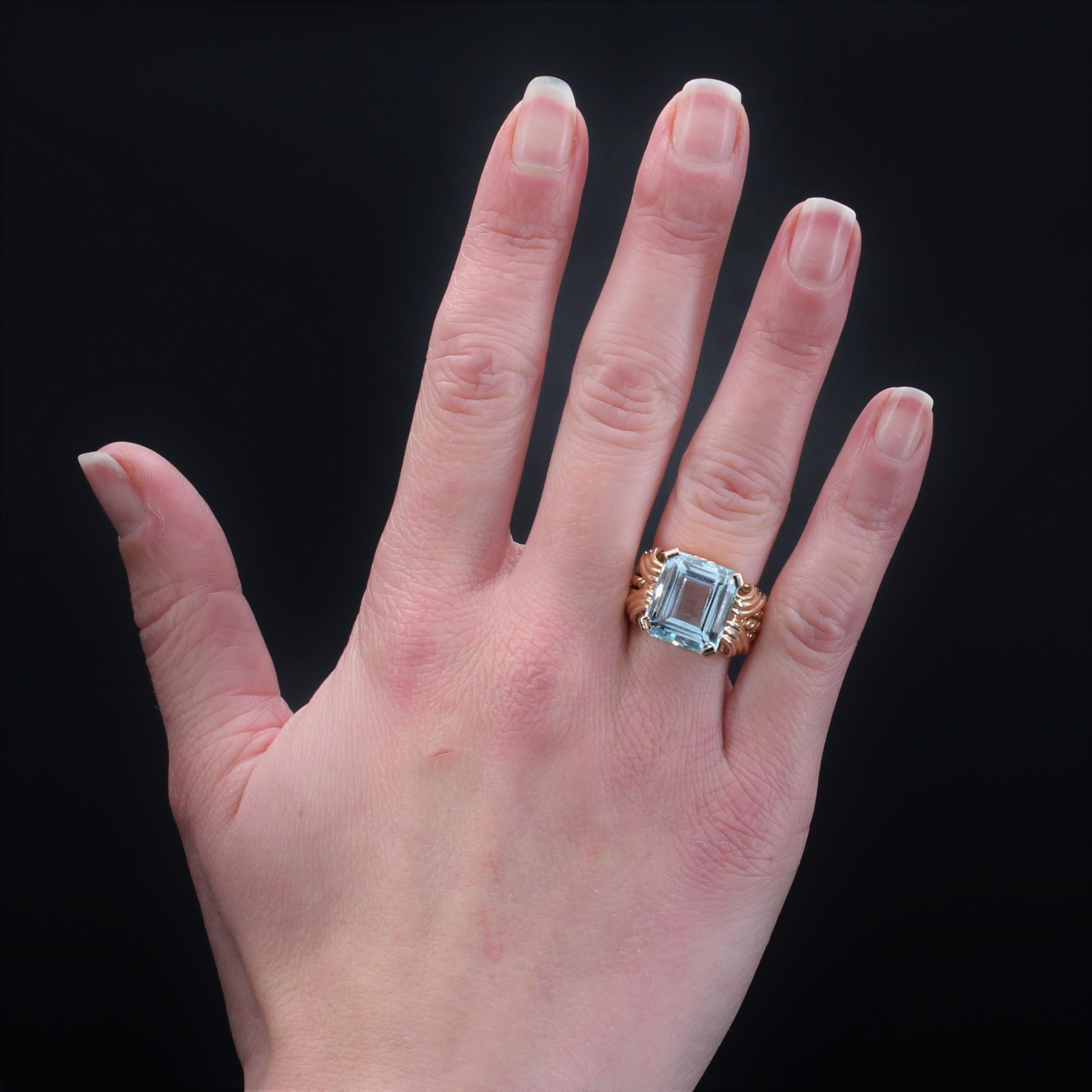 Ring in 18 karat rose gold, eagle head hallmark.
Voluminous retro ring, its body is made of 5 twisted rings that meet on top. A degrees- cut aquamarine is held to 4 flat claws and held on either side of 2x2 patterns of gadrooned waves.
Weight of the