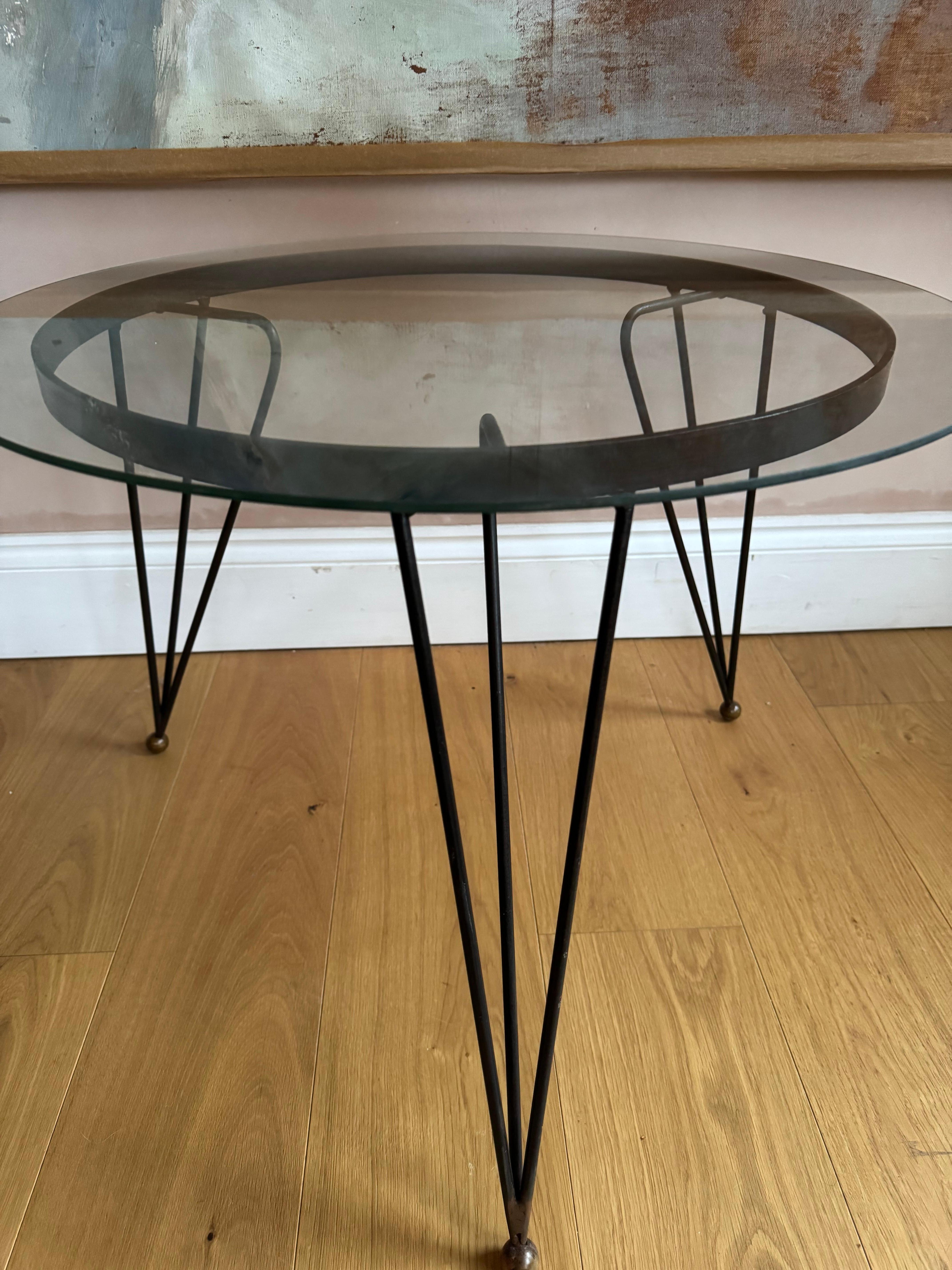 Table d'appoint en métal noir à base de trépieds, avec plateau en verre d'origine. Il n'y a pas d'éclats mais le verre présente des rayures superficielles.