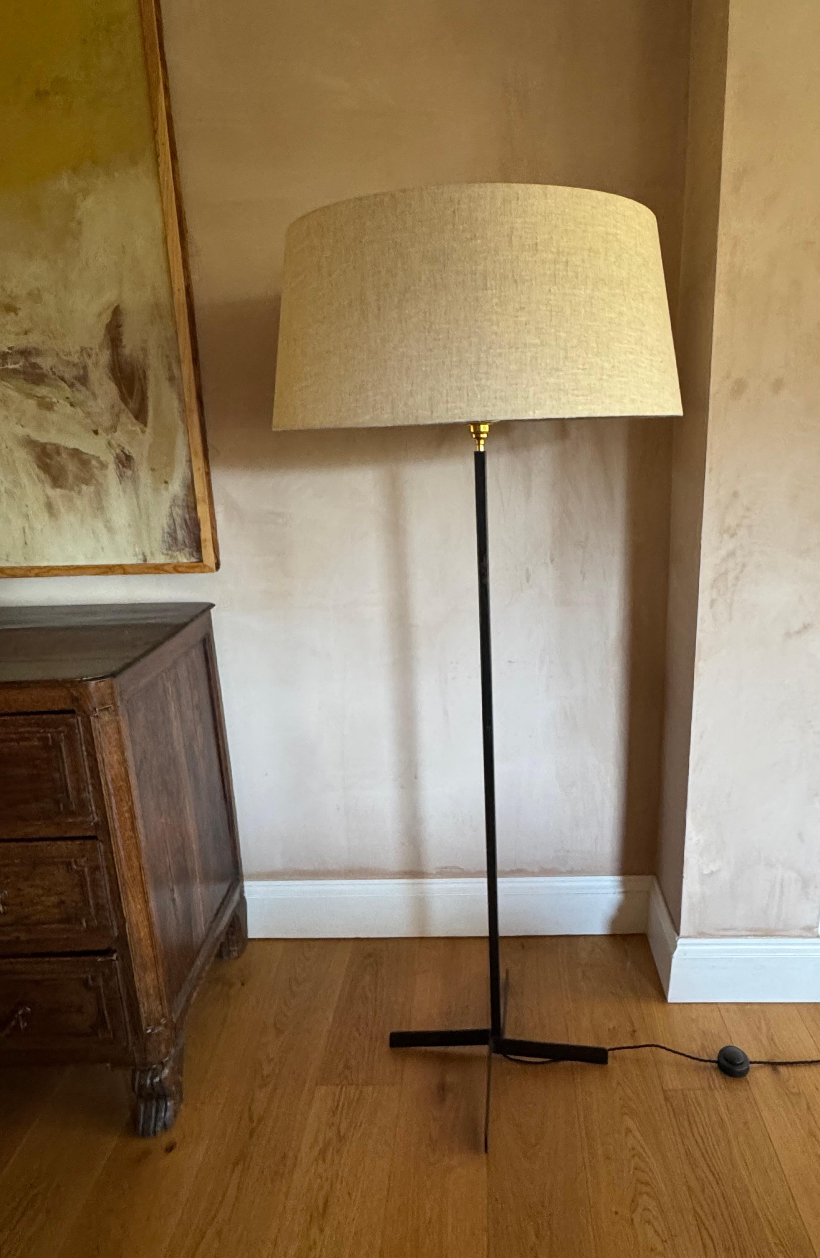 Lampadaire français des années 1950 en métal noir avec une base en métal croisé. Solides et robustes. Montrée avec un grand abat-jour en lin pour l'exposition, non inclus. 