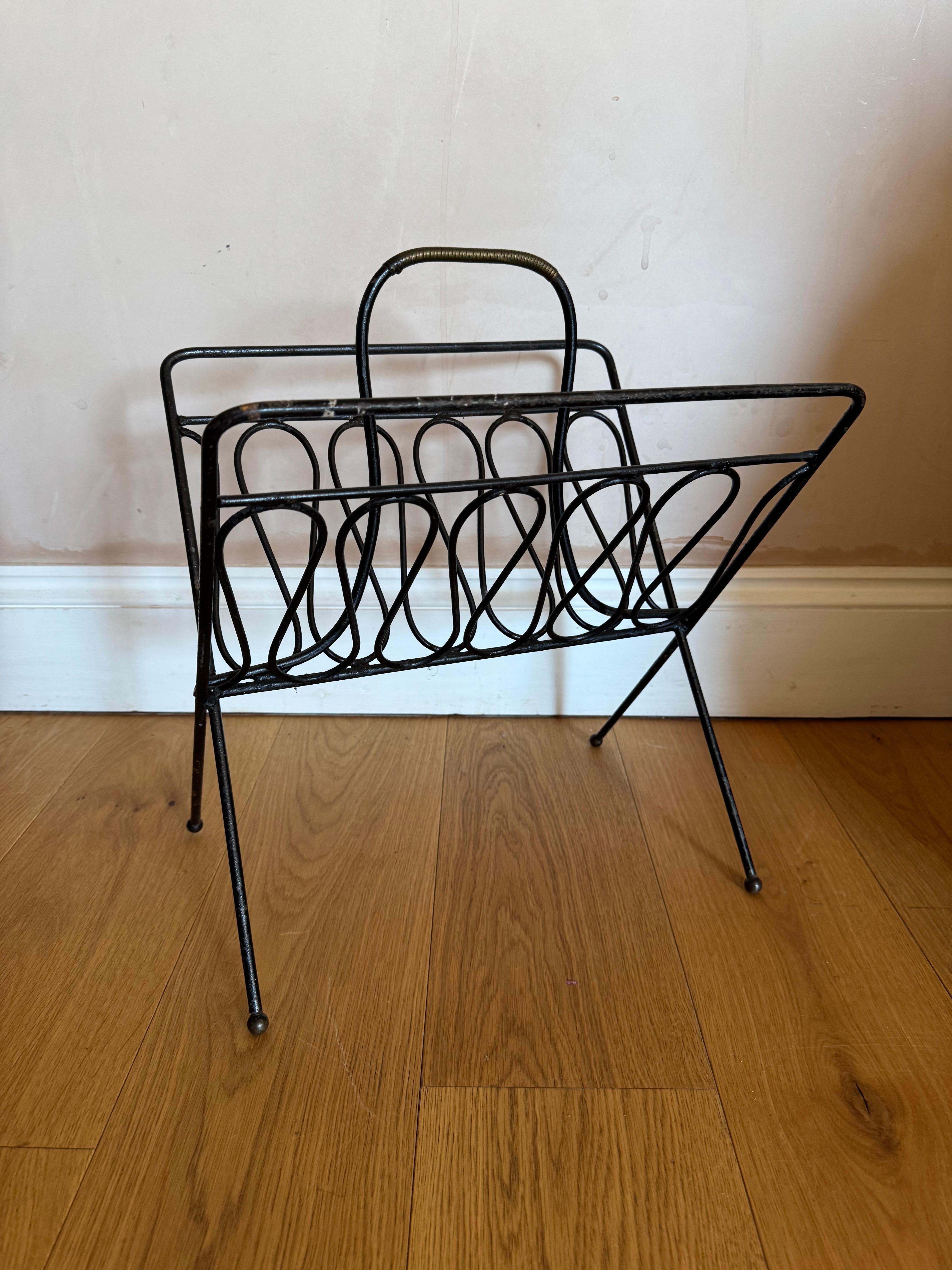 Elegant French 1950’s black metal magazine rack with brass ball feet and rope effect detail on the handle. 