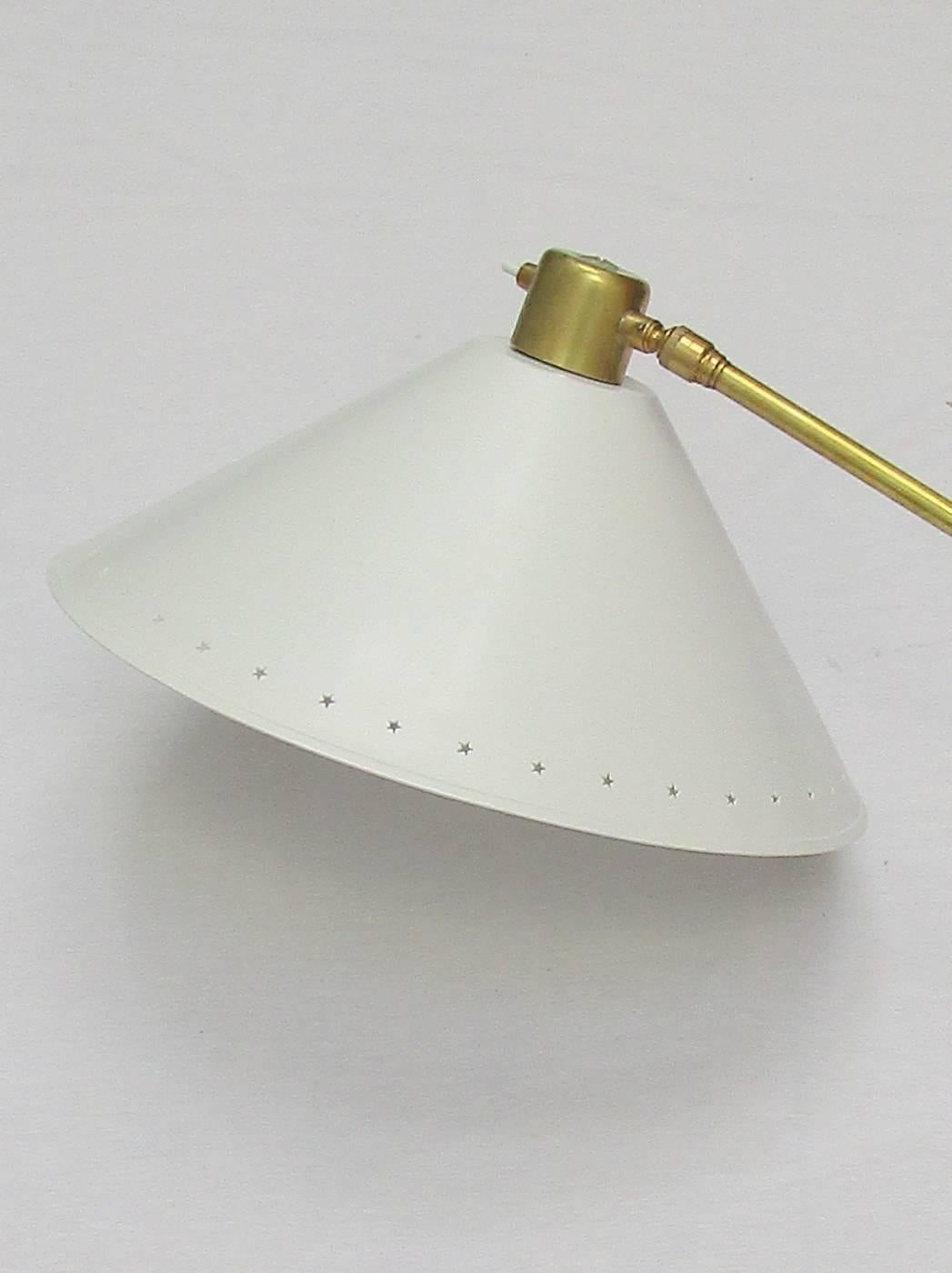 A French 1950s pivoting brass wall light with adjustable lacquered metal cone shade with pierced star decoration. Designed by René Mathieu for Lunel
Re-wired and PAT tested.
 