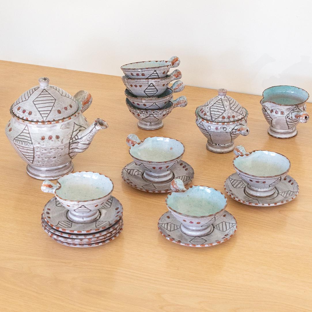 Unique ceramic tea set made by French ceramic maker Vallauris in the 1950's. Set includes 1x large tea pot with lid, 1x sugar bowl with lid, 1x creamer bowl, and 8x tea cups with saucers. Pieces are made of red clay with a white glaze and etched