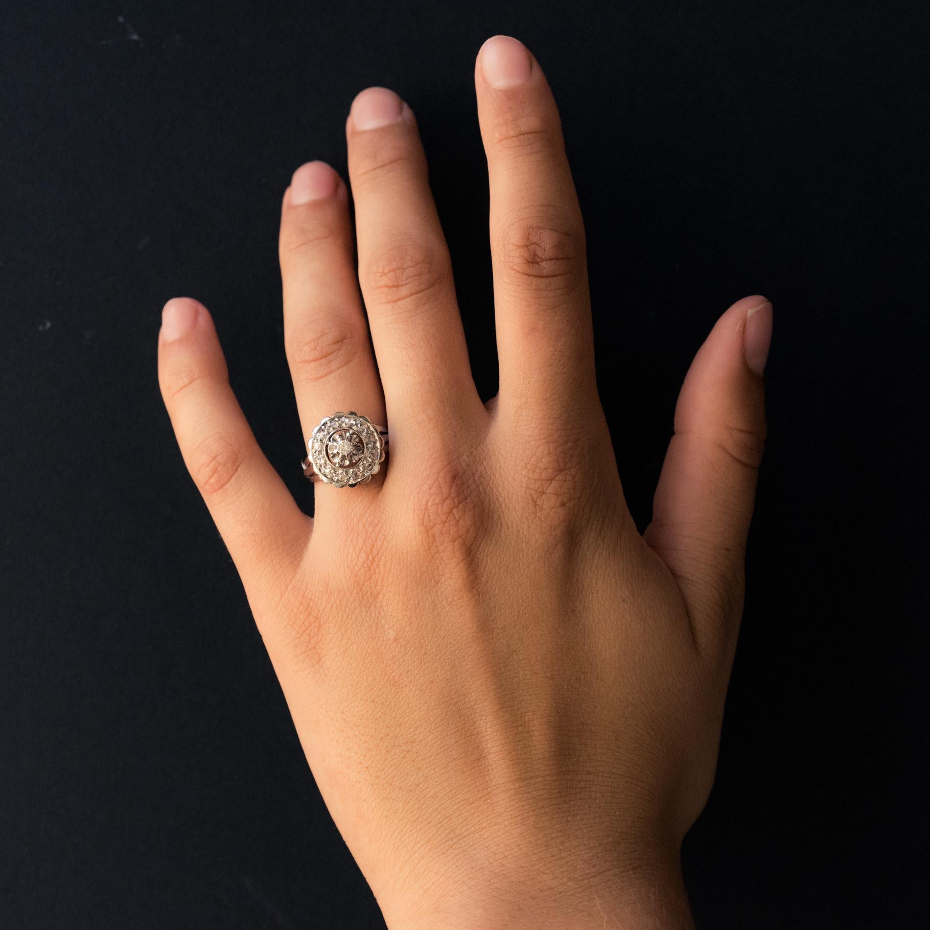 Ring in 18 karat white gold, eagle's head hallmark.
Round in shape, the slightly raised and pierced mounting is set with rose- cut diamonds and at its center, a modern brilliant- cut diamond retained with claws. The ring is made up of three flat