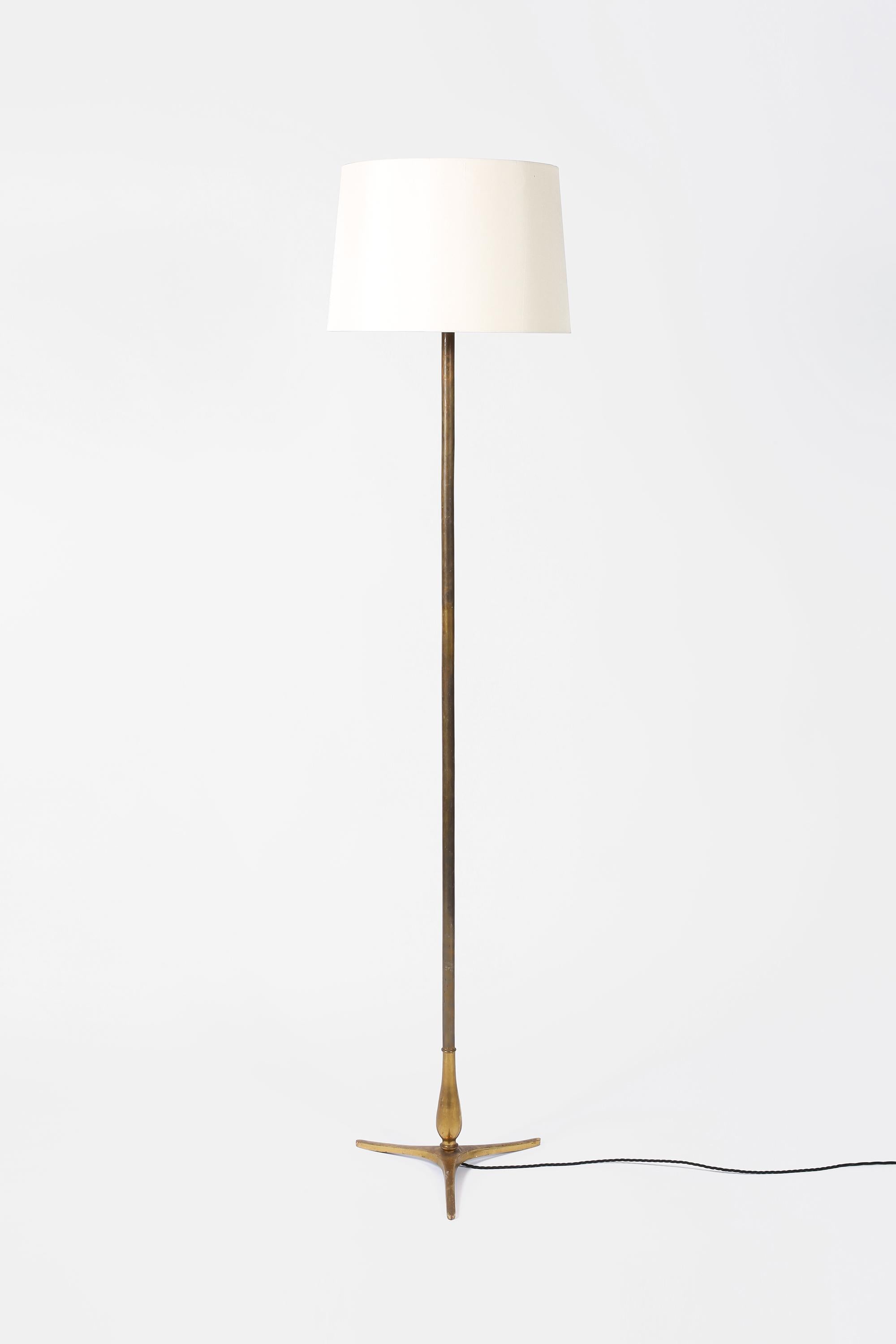 Eine Stehlampe aus patiniertem, vergoldetem Messing mit einfachem Stiel und formschönem Dreipunktsockel aus Bronzeguss. Französisch, ca. 1950er Jahre. Wird mit einem Schirm aus cremefarbener Dupionseide geliefert.