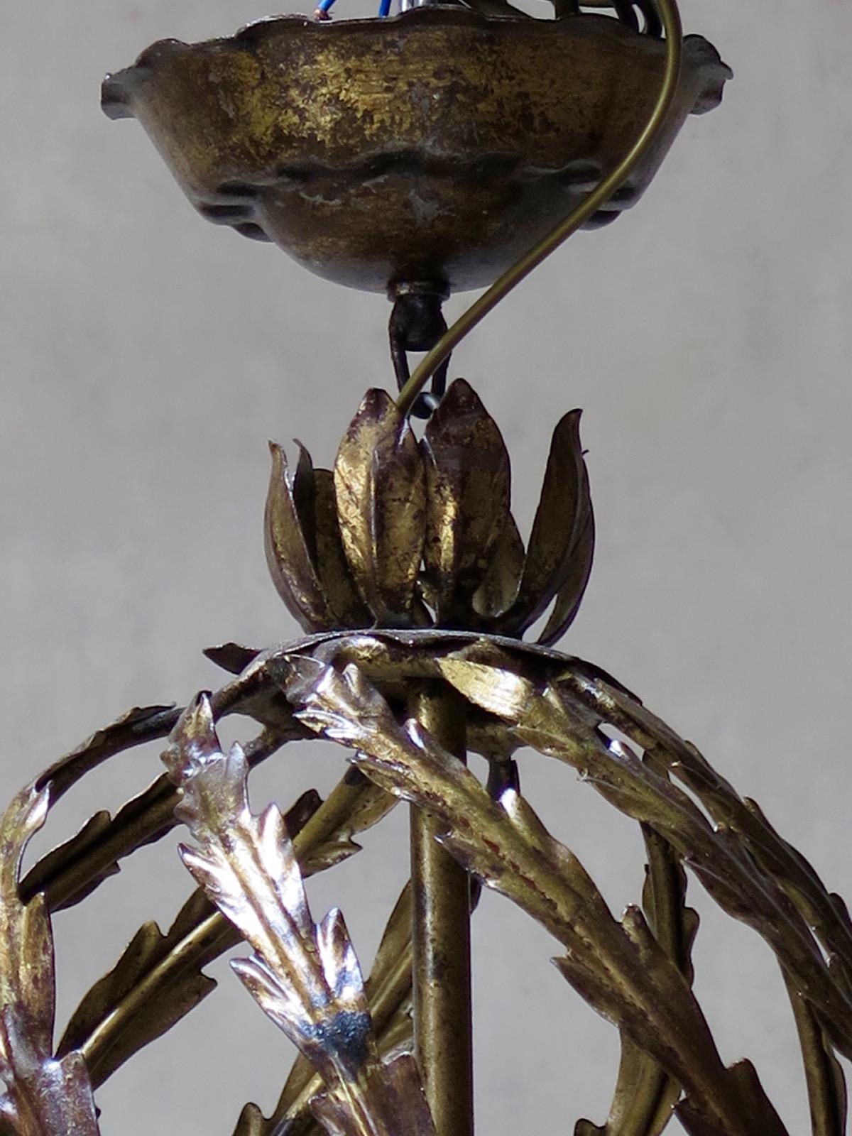 French midcentury gilt iron chandelier, with an elegant, bulbous centre part composed of multiple twirling rods, adorned with leaves. The arms extend down and out in an elegant, sweeping movement.