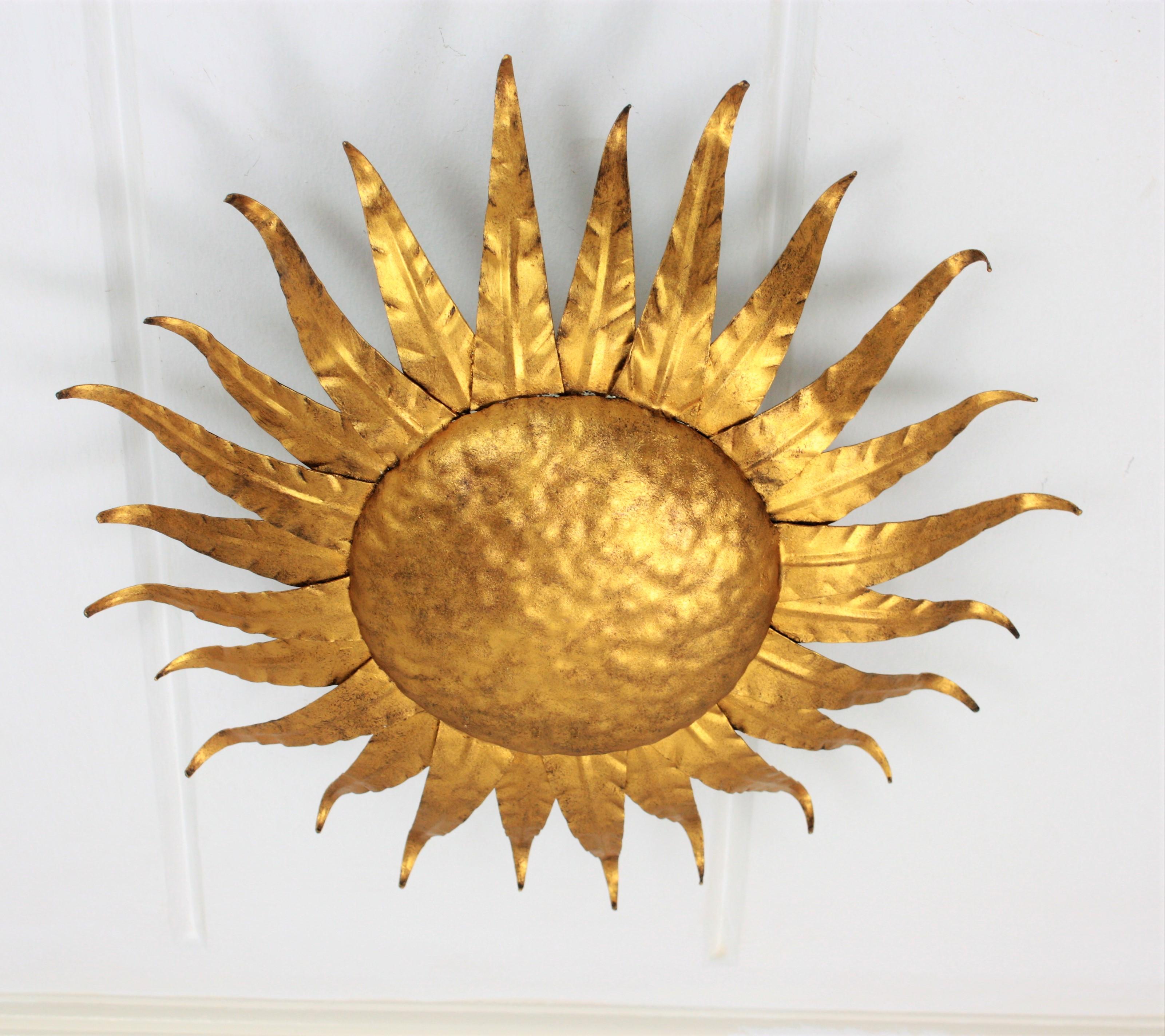 A hand-hammered iron sunburst ceiling light fixture or wall sconce with gold copper finish. Beautiful to place alone as ceiling or wall sconce, but also stunning mixed with other pieces in this manner to create a wall decoration, France, 1950s.

 