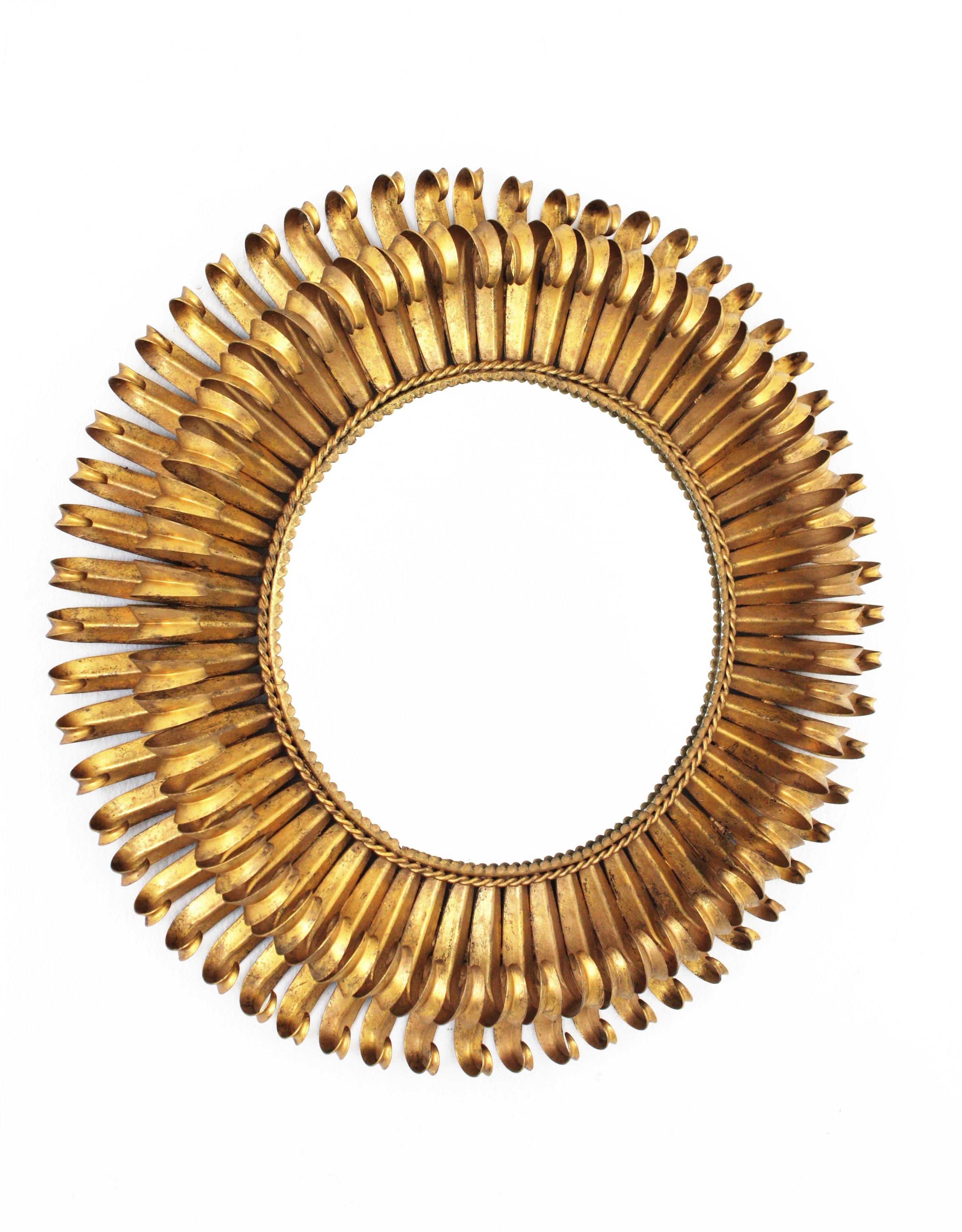 Lovely 1950s hand-hammered double layered eyelashed gilt iron sunburst mirror with gold leaf finish and circular shape.
The frame is made by a double layer of curved beams in eyelash shape that makes the piece highly decorative. It has a beautiful