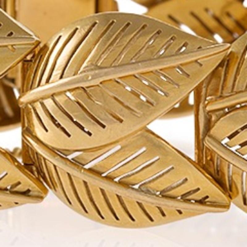 Created mid-20th century, this hinged French gold bracelet is formed of leaf motif links. The bracelet’s gold, overlapping double leaves are designed with open, negative spaces. As a naturalistic design with a touch of modernist abstraction and fine