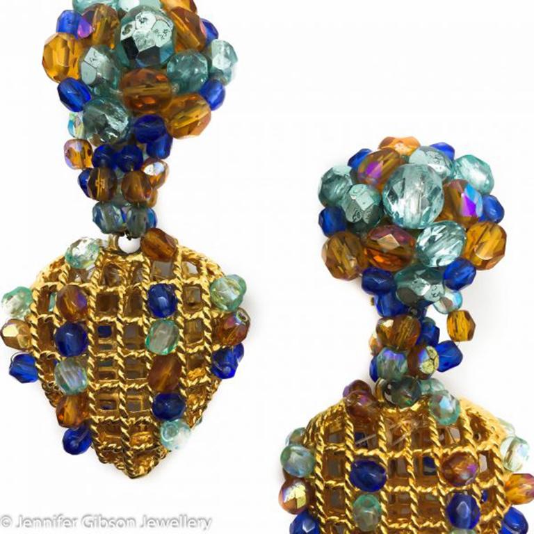 A pair of French earrings, dramatic yet delicate, gilt baskets, adorned with beautifully colored crystal beads of amber, aqua and deep blue. Truly a fabulous color combination - distinct and elegant. A fat shaped heart bejeweled gilded cage hangs