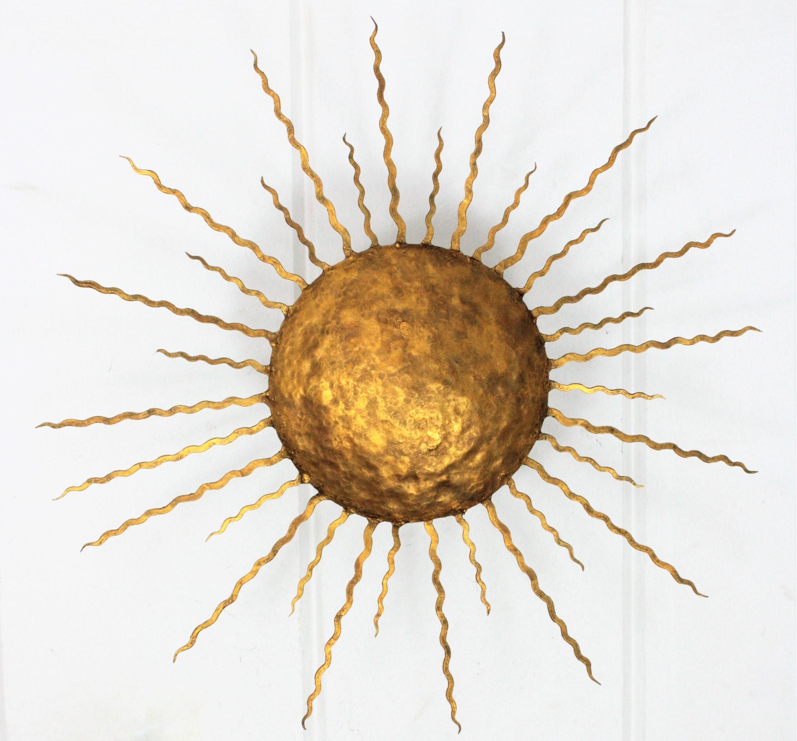 Beautiful hand-hammered gilt iron wall light or ceiling light with Brutalist accents. France, 1950s
Richly decorated with hand-hammered marks. It has curly flat iron rays in two sizes surrounding the central sphere. It can be placed as ceiling light